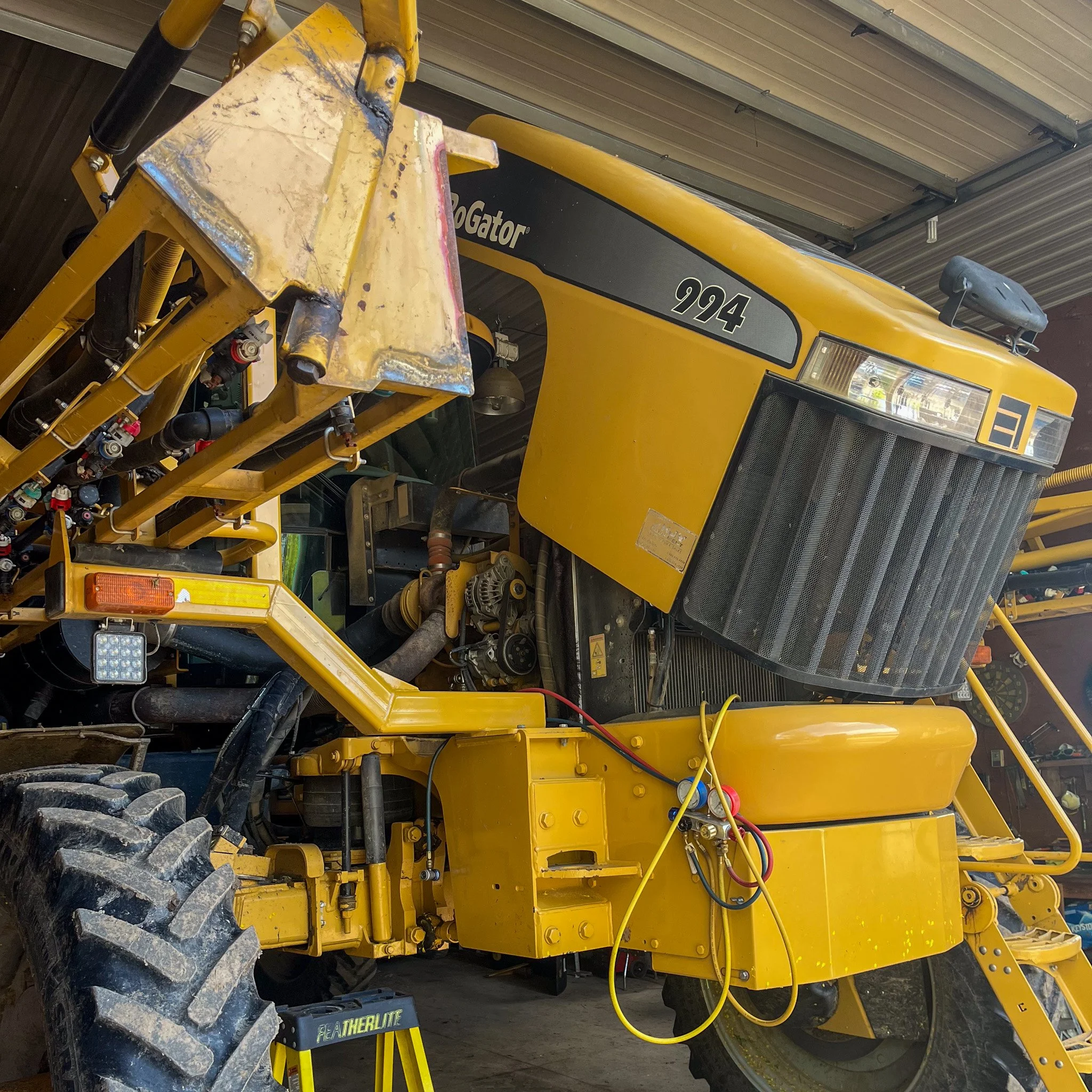 Close-up of a yellow Caterpillar 994 wheel loader inside a garage, showing its front bumper, part of the engine, and large tires.