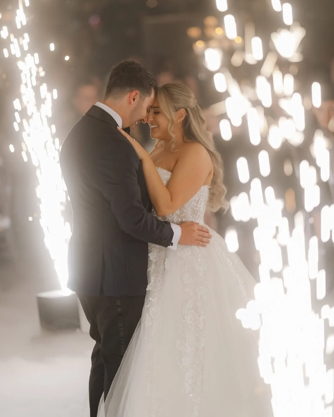 A bride and groom share a romantic dance at their wedding reception, surrounded by sparklers.