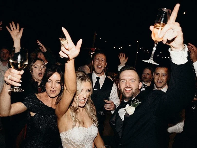 People celebrating at a wedding reception, raising glasses of champagne, with joyful expressions.