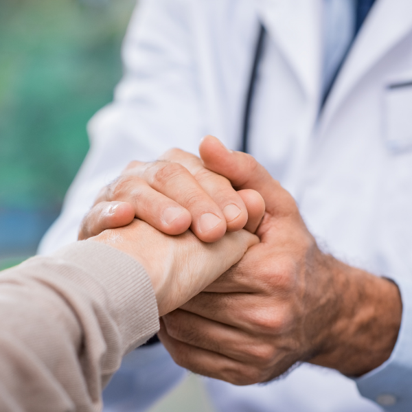 A doctor holding a patient's hand during a consultation or comforting gesture.