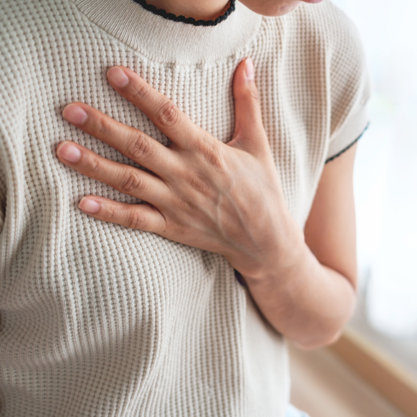 Person holding hand on chest, wearing a beige knit shirt.