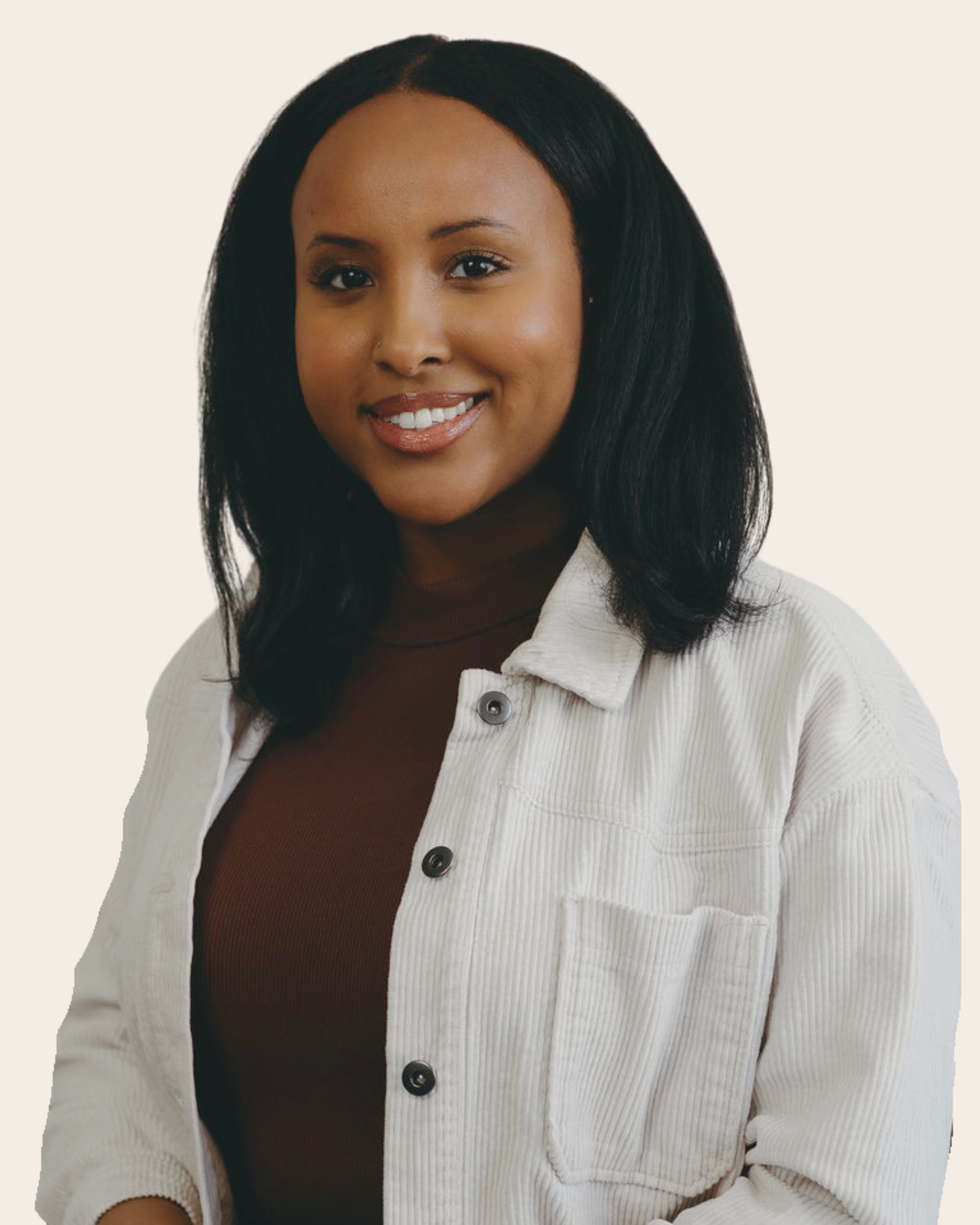 A woman with medium skin tone, shoulder-length black hair, smiling, wearing a white corduroy jacket over a brown top, against a cream background.
