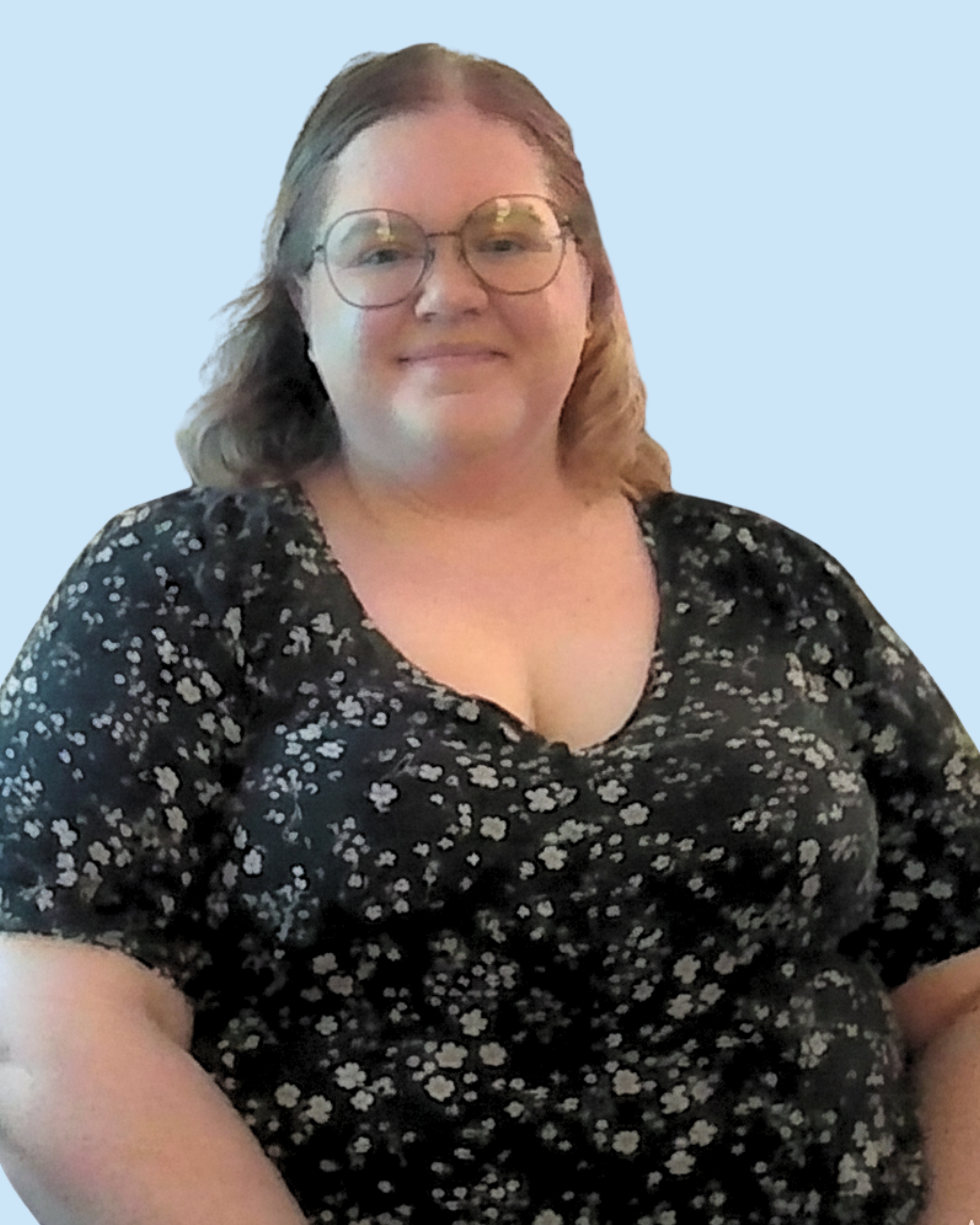 A woman with glasses and wavy brown hair smiling, wearing a black floral dress, posed against a pale blue background.