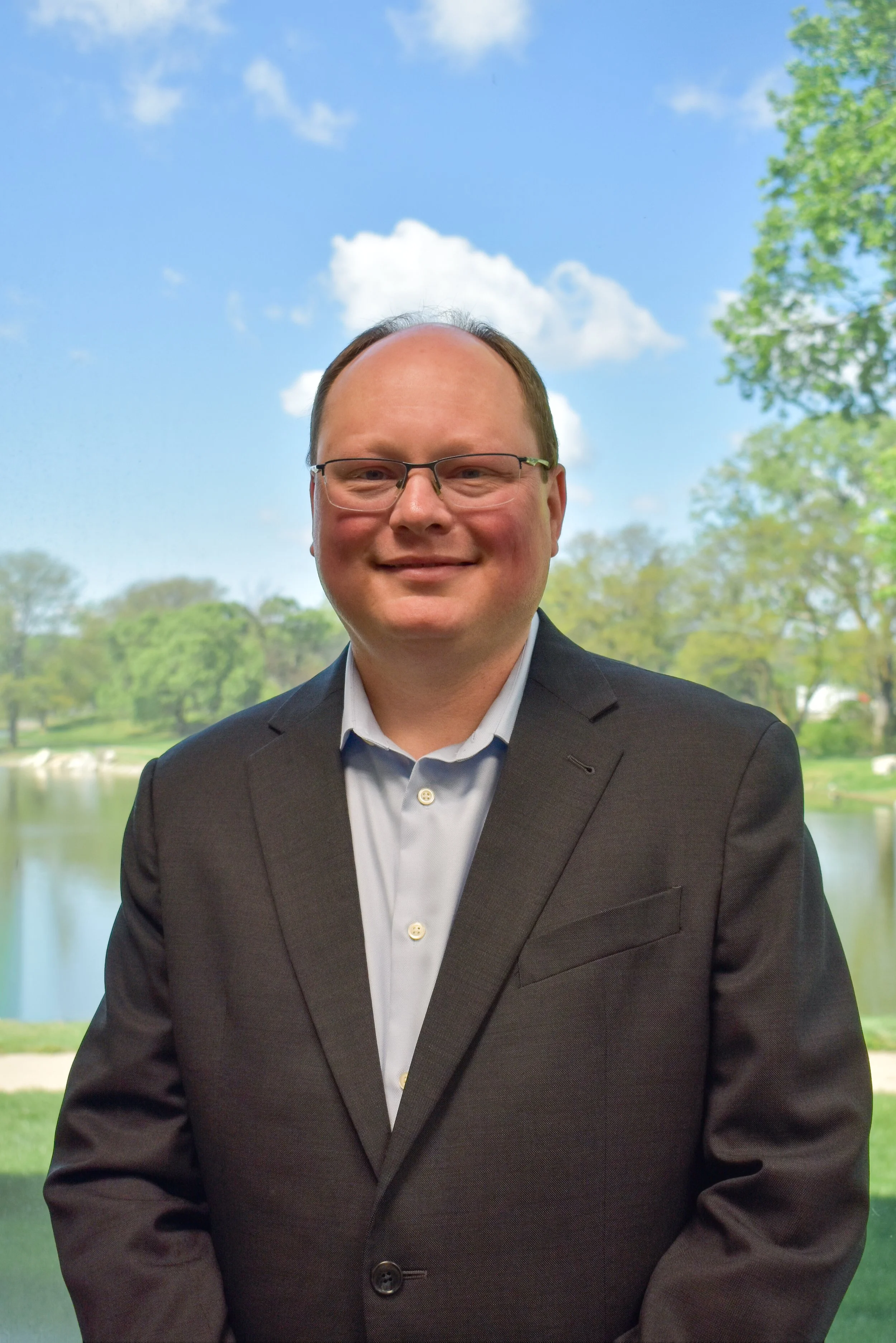 Black and white portrait of a man wearing glasses, a suit, and a patterned tie.