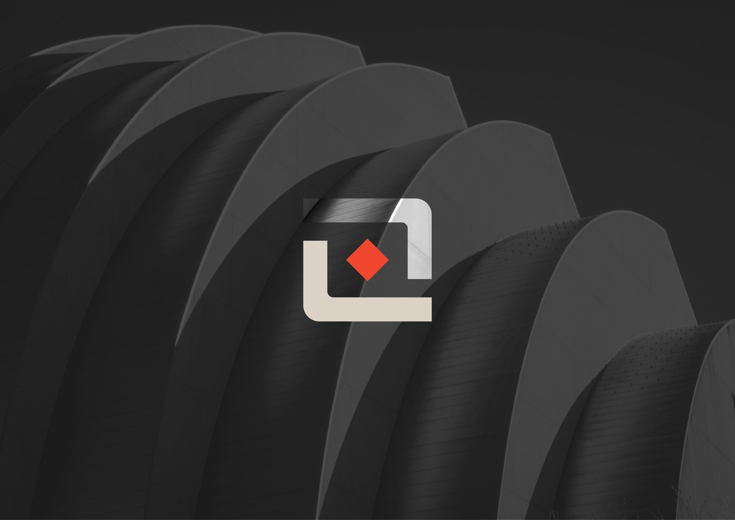 A black and white modern architectural building with curved, overlapping panels and a superimposed logo featuring a stylized corner with a red diamond shape in the center.