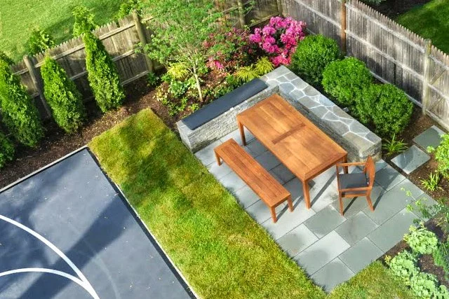Planting Design | Image of a stone seat wall with outdoor furniture on a bluestone patio