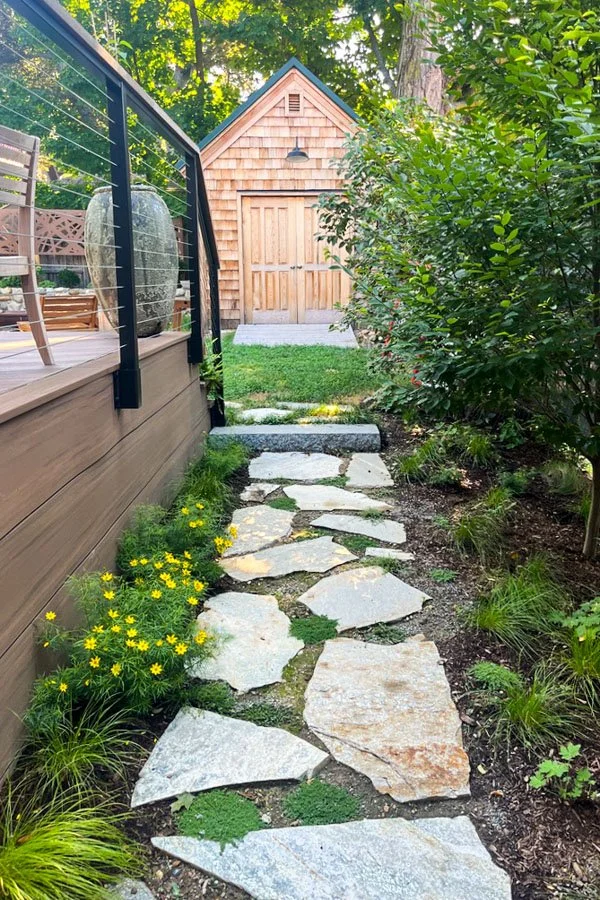  Stone path with composite wood deck and railing and screen hedge 