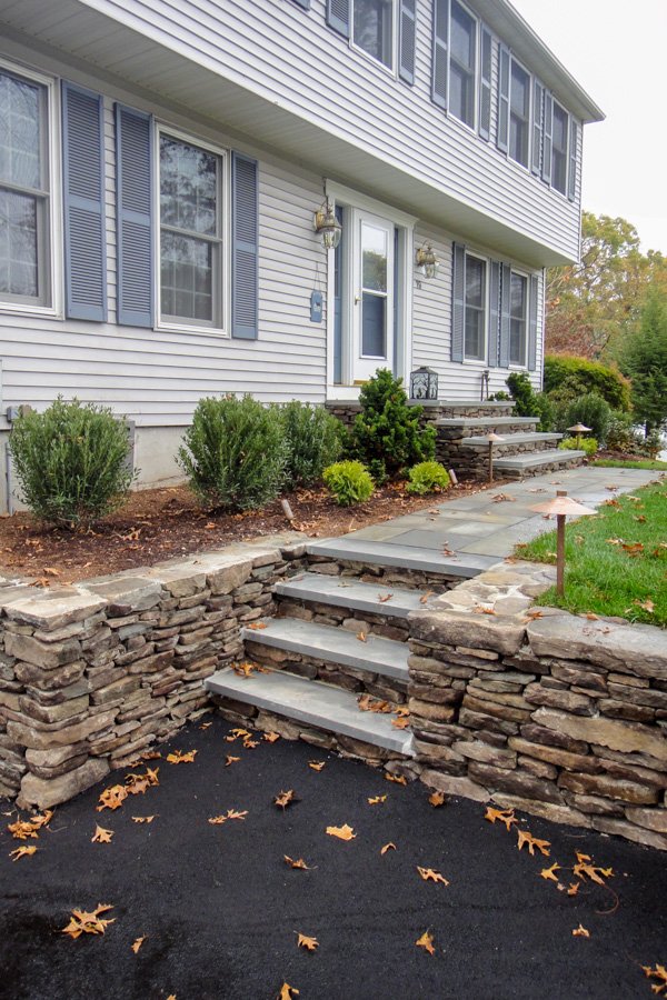  Low stone retaining walls with bluestone capped treads and bluestone front path 