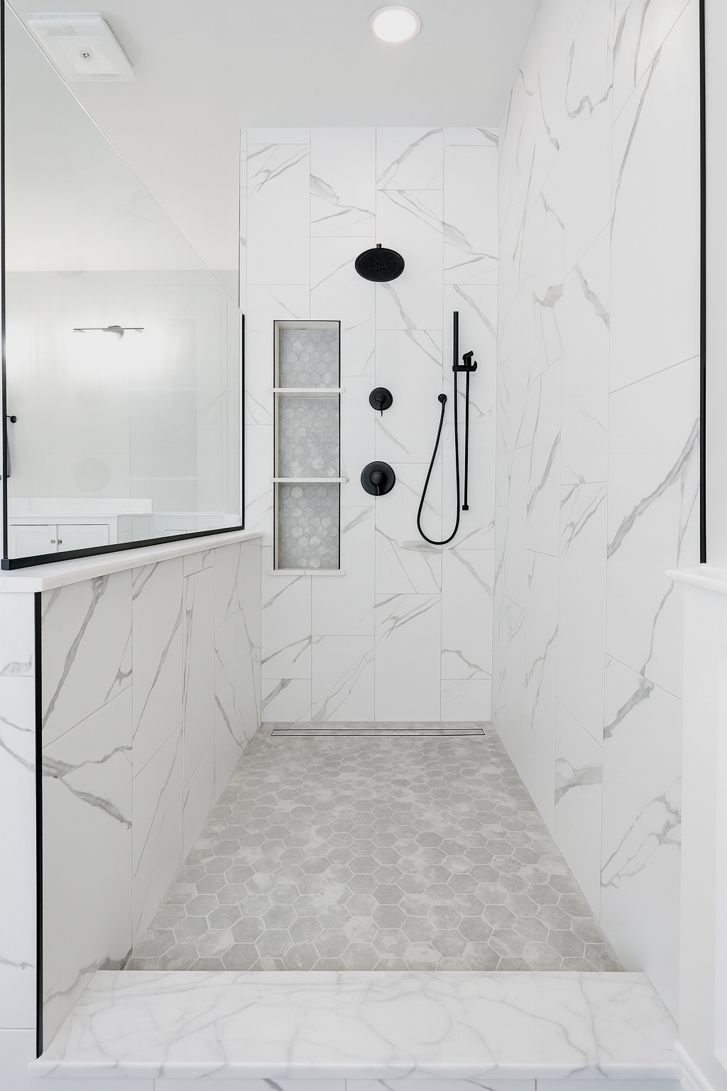 Modern walk-in shower with white marble walls, black fixtures, hexagonal tiled floor, and a small built-in niche.