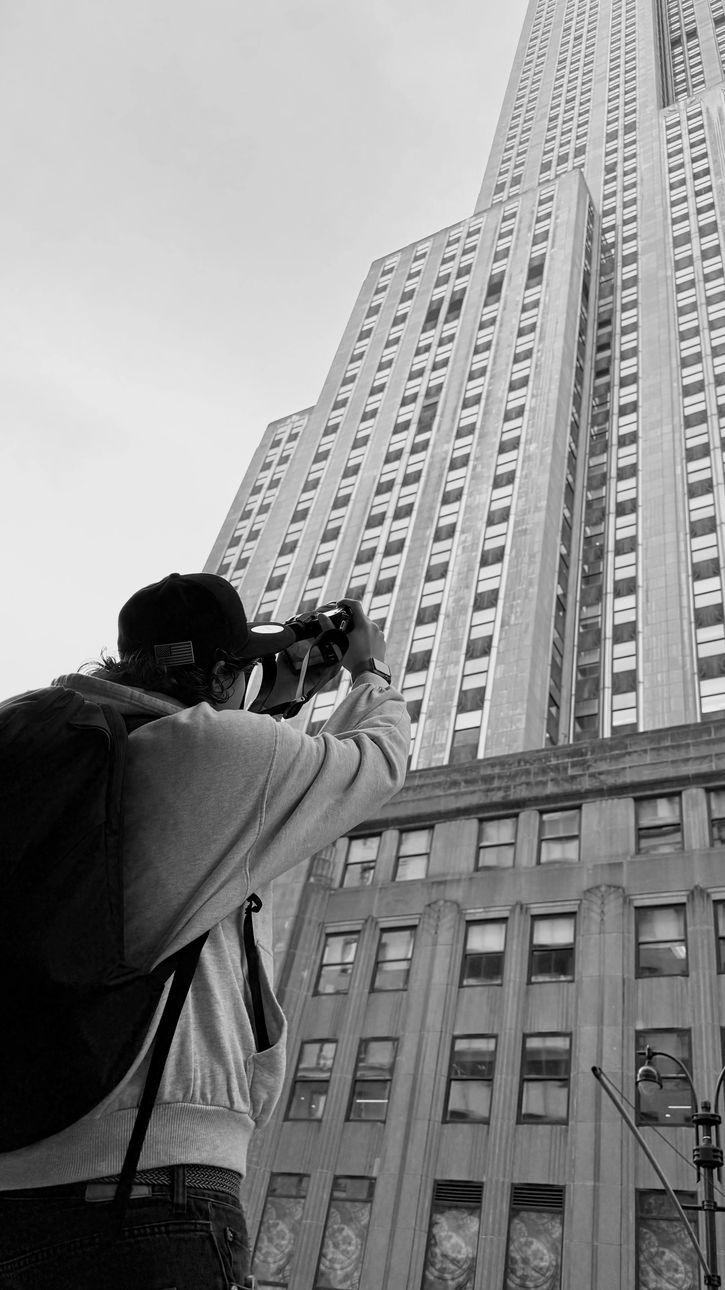 Un homme avec un sac à dos photographie un gratte-ciel dans une ville