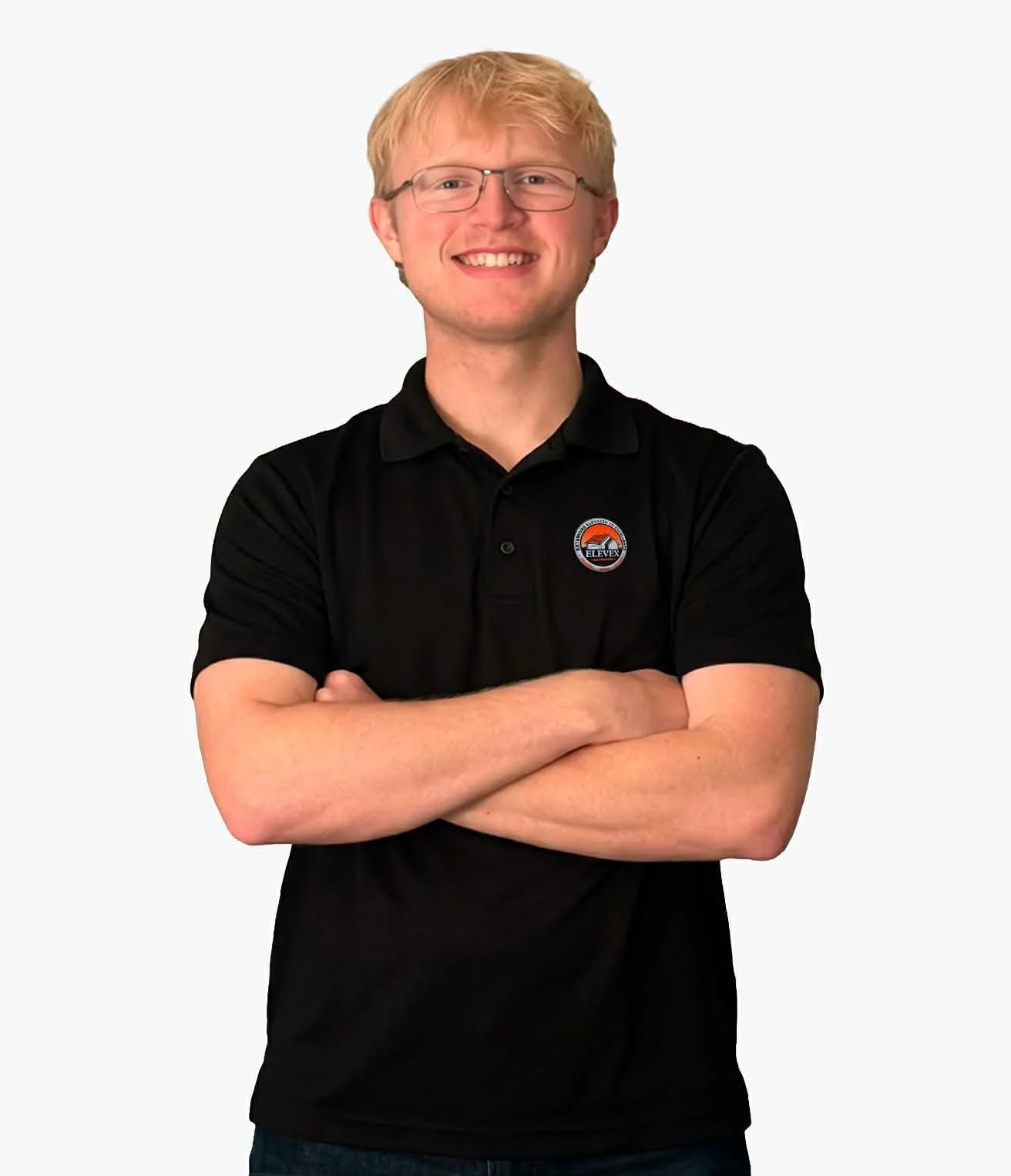 A young man with glasses and blond hair smiling, arms crossed, wearing a black polo shirt with a logo, standing against a plain white background.