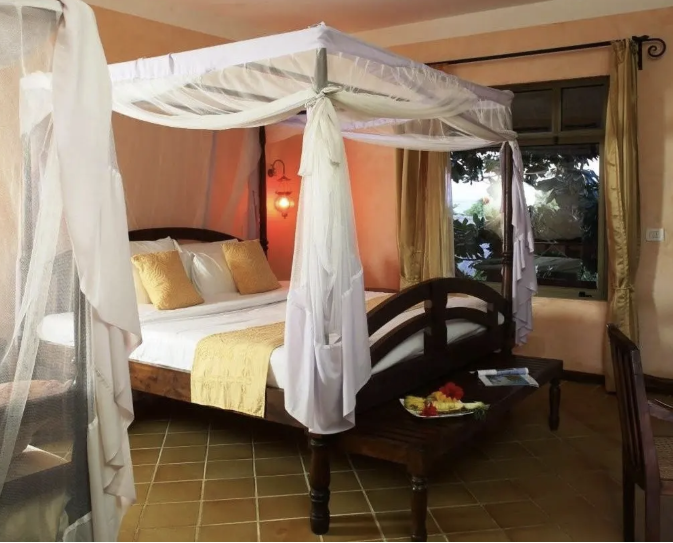 Camera da letto con letto a baldacchino, coperte dorate, cuscini dorati, finestra con tende gialle, pareti rosa e luce soffusa.