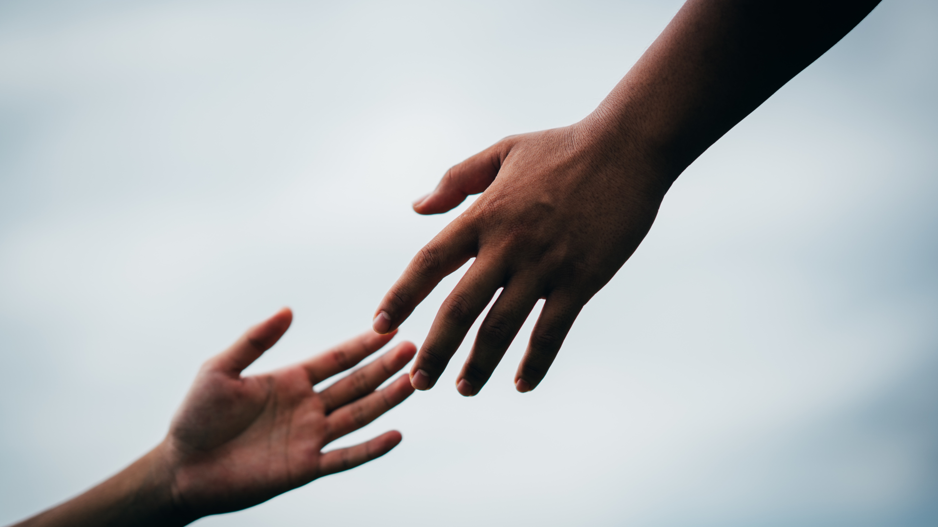 Hands Reaching out for each other. Diverse background, blue sky.