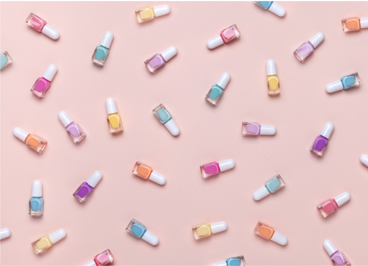 Scattered nail polish bottles in pastel colors on a pink background.
