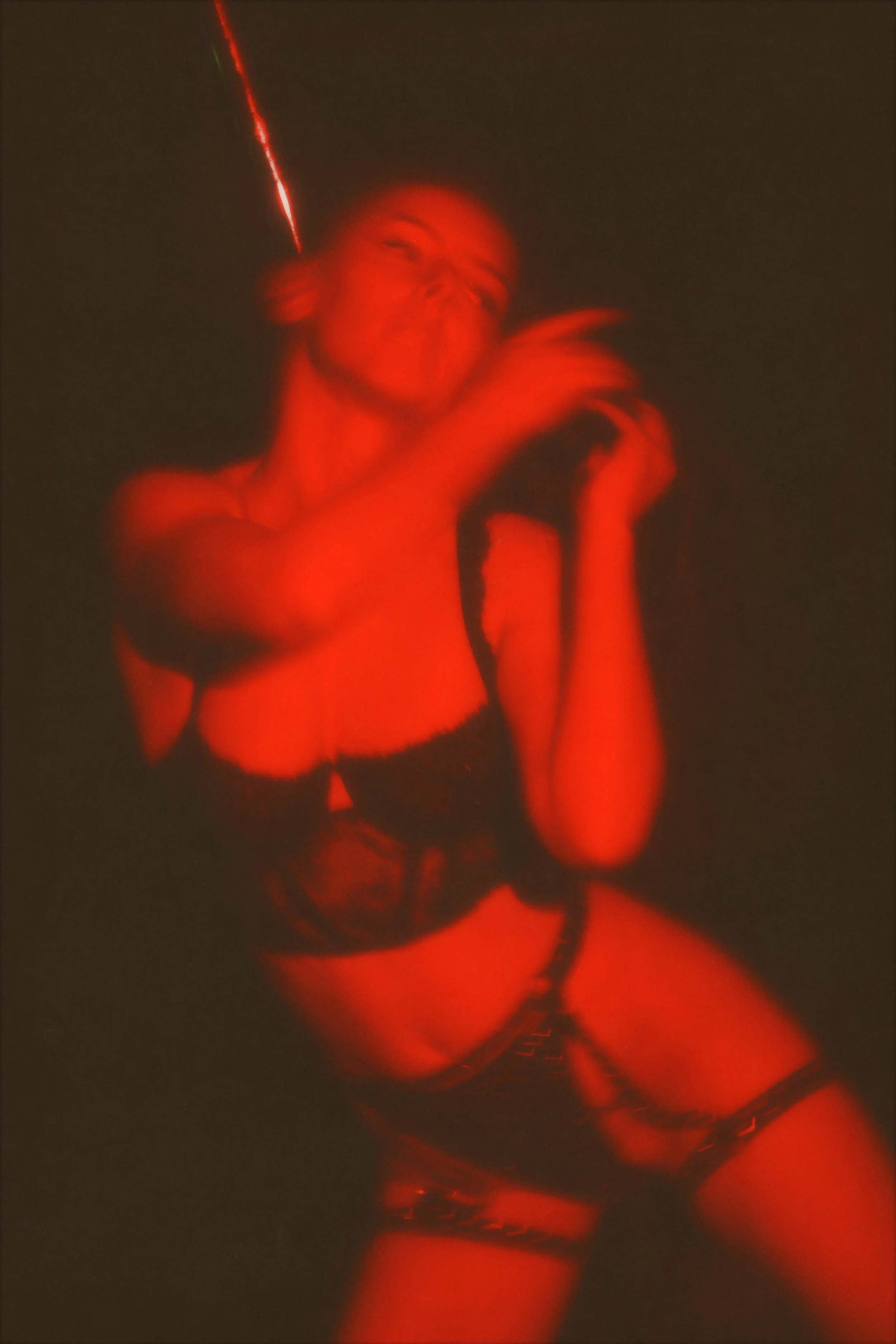 Vihreä ja punainen laservalo ja nuori nainen, joka poseeraa mustassa alusvaatteissa pimeässä huoneessa.