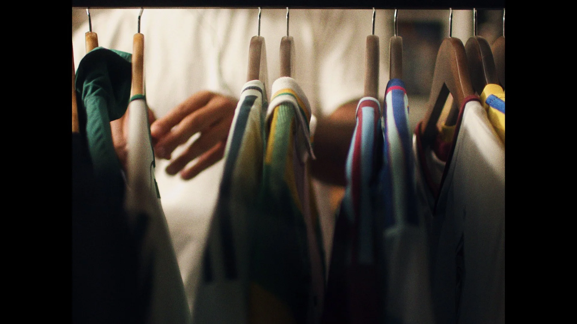 A person is browsing through colorful baseball caps on hangers in a store.