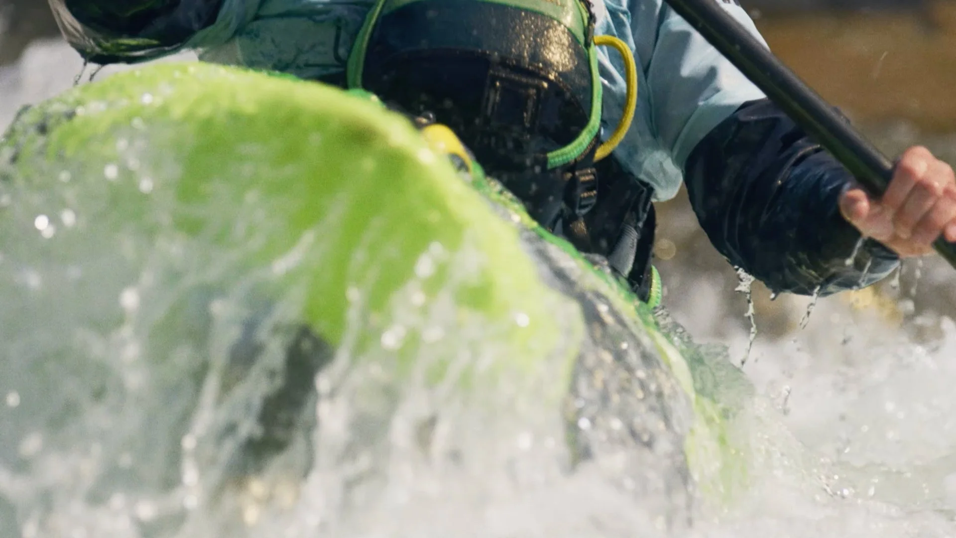 Close-up of a person in water, holding a paddle, with a large green leaf in the foreground.