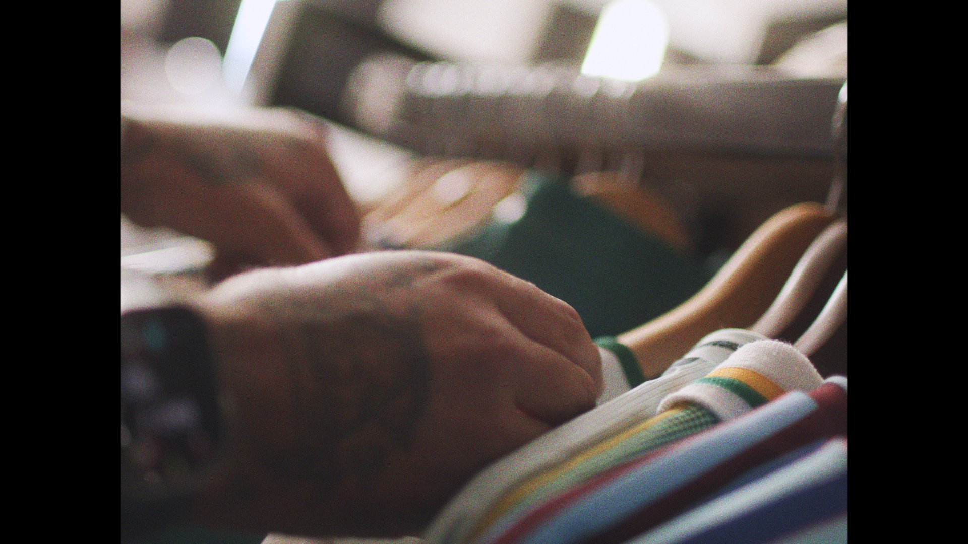 Person browsing through striped clothing on a rack in a store.