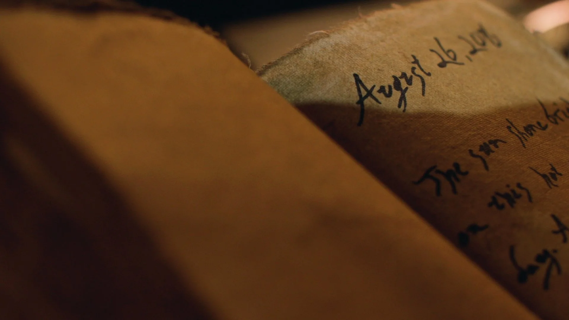Close-up of an ancient manuscript or scroll with handwritten text in black ink on brown parchment paper.