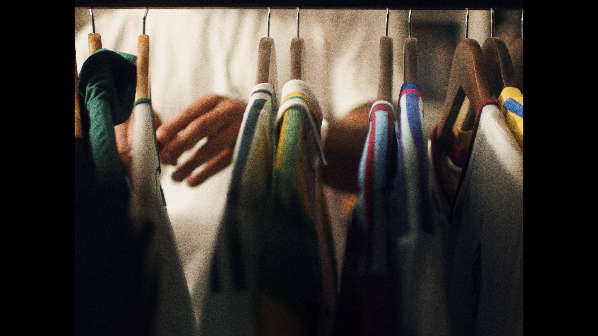 A person browsing or choosing printed T-shirts hanging on a clothing rack.