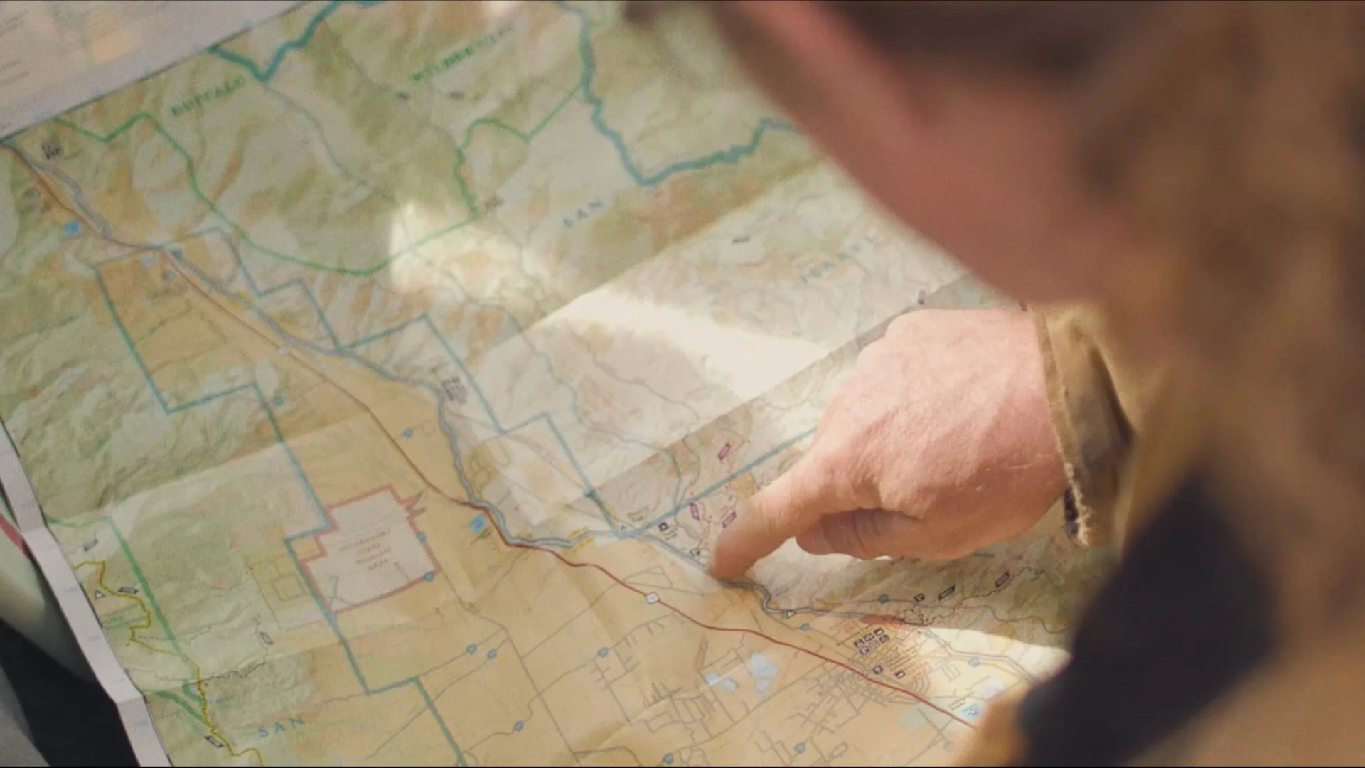A person points at a detailed topographic map with marked trails and geographical features.