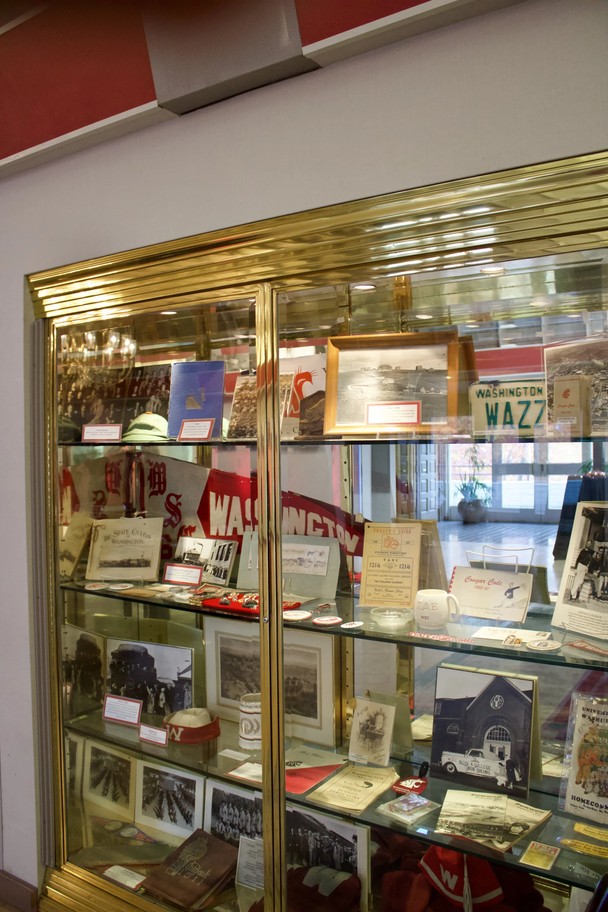 Display case with historical memorabilia, photographs, books, and Washington WAZ memorabilia, inside a museum or similar setting.