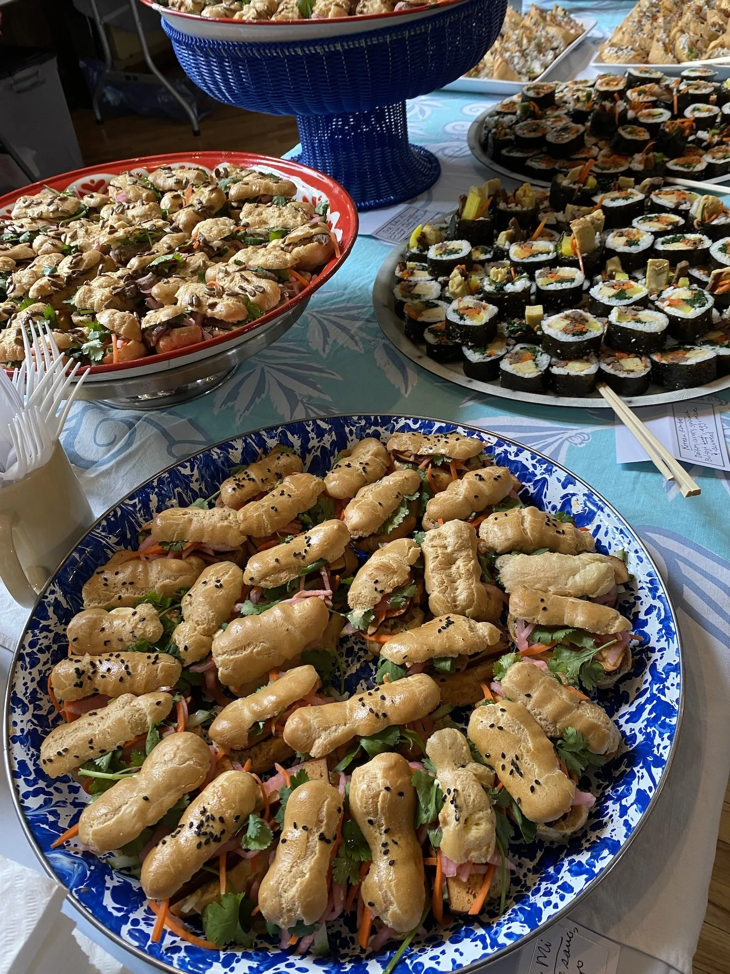 Assorted sushi and Asian-style finger foods arranged on a table for a buffet at an event catered by Leaf Kitchen.