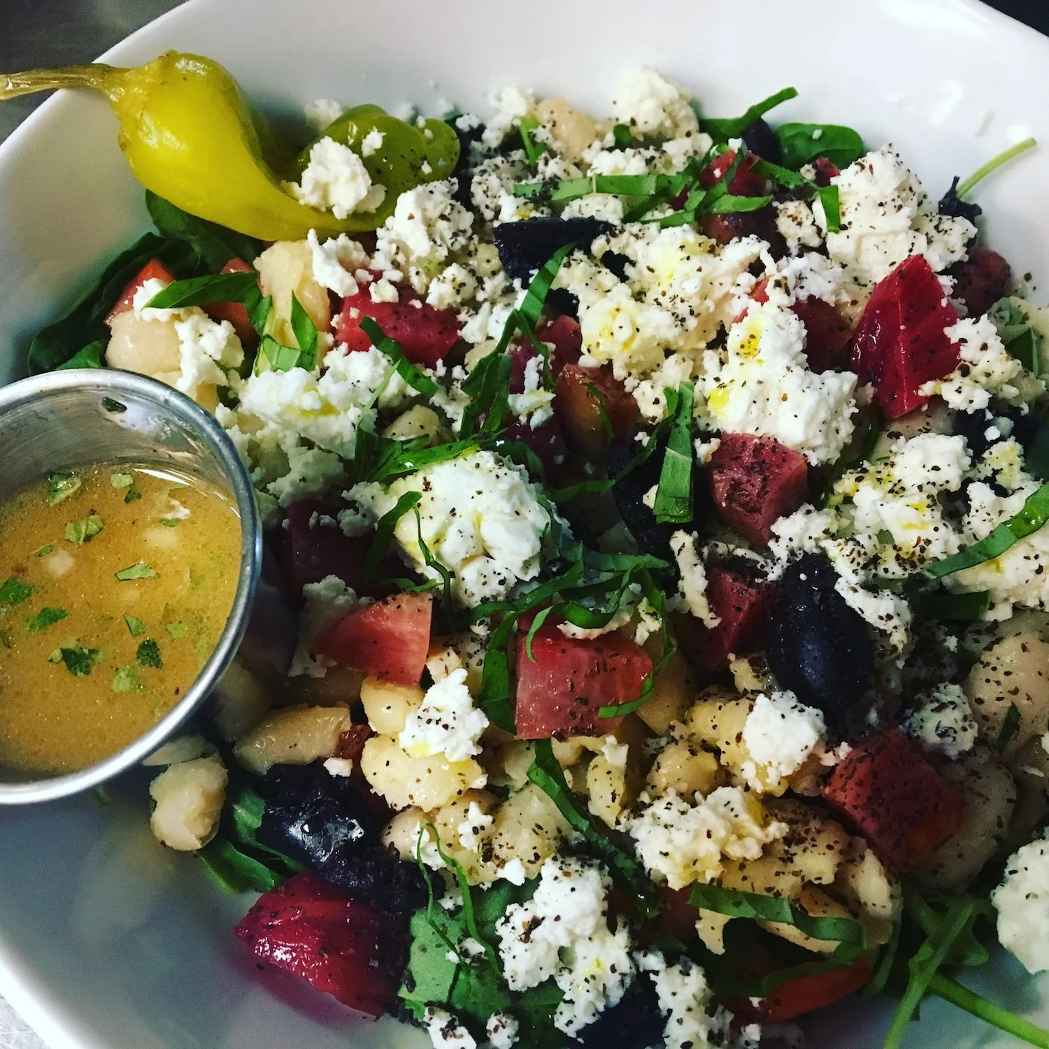Meal from Leaf Kitchen: A salad with fresh vegetables, crumbled cheese, herbs, and a small container of dressing.