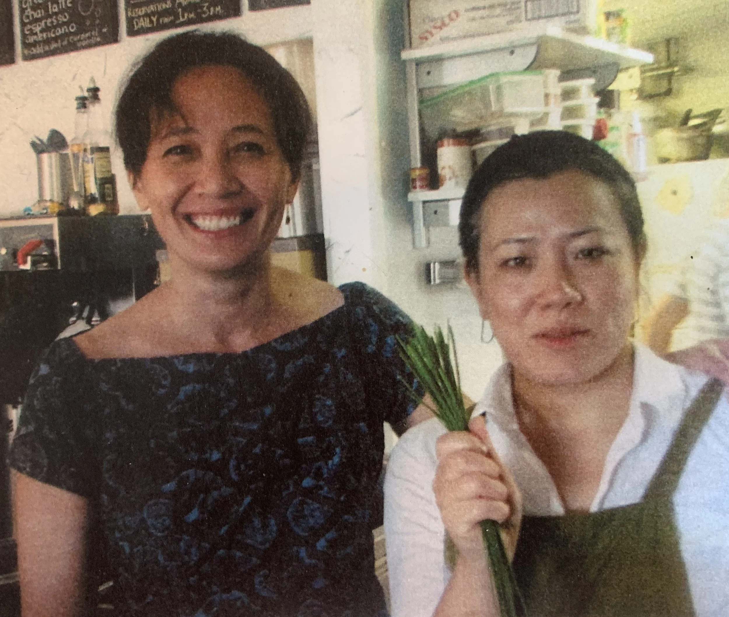 Harriet Woodford and Masae Judge of Leaf Kitchen, standing in kitchen. Masae holds a handful of chives.