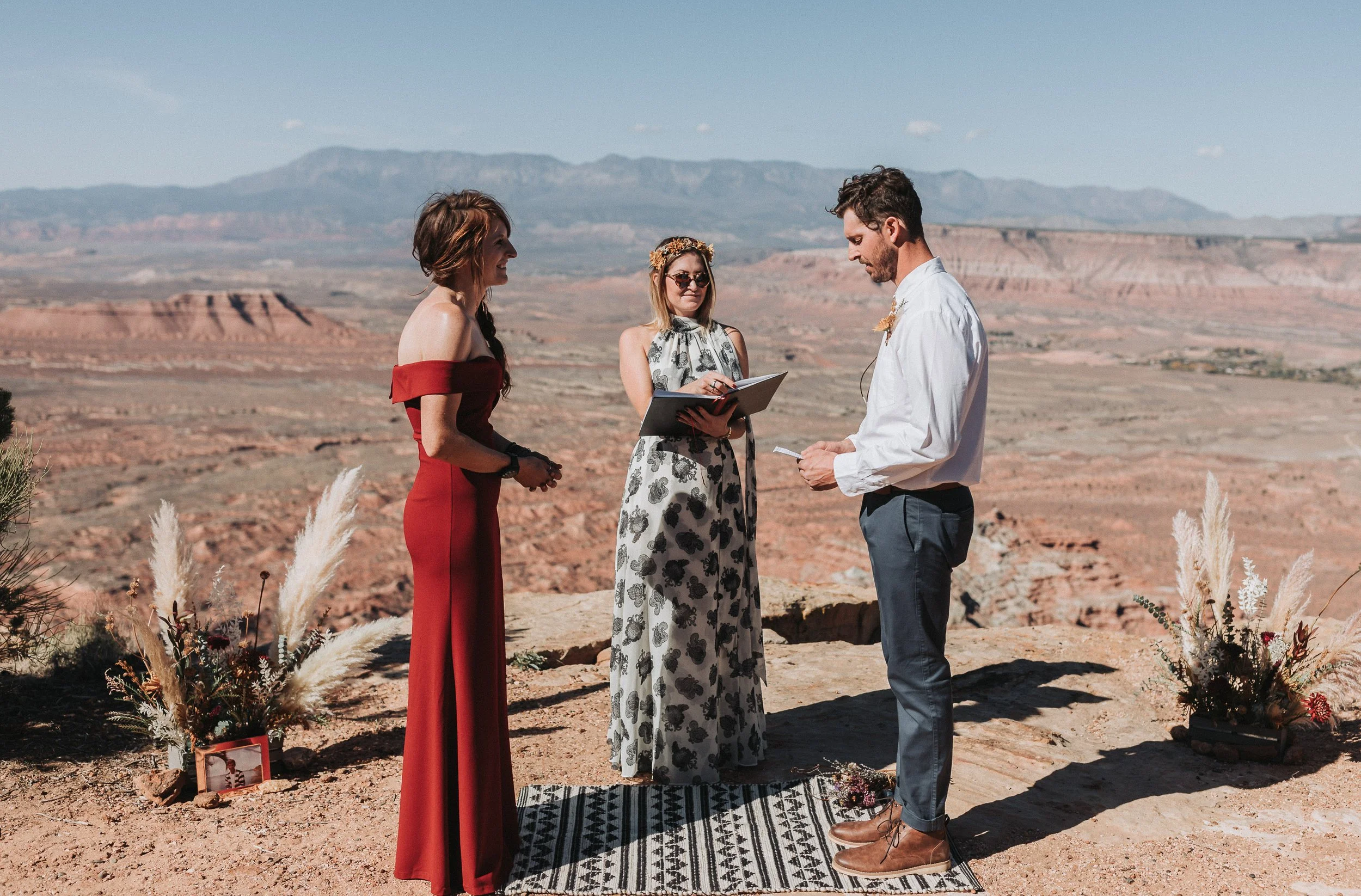 A wedding ceremony taking place outdoors in Southern Utah on a rocky landscape with mountains in the background.