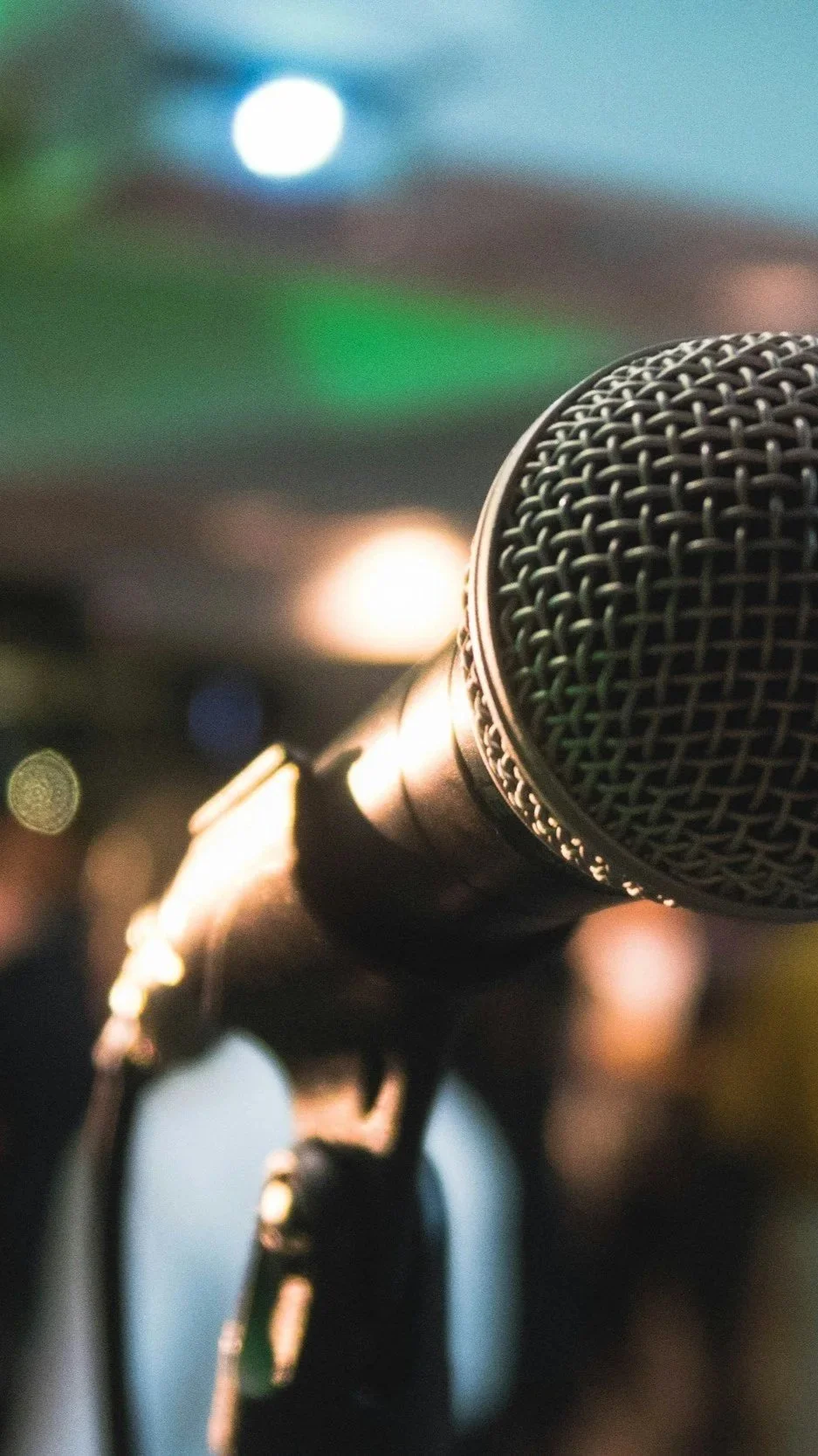 Close-up of a microphone with a blurred background of stage lights.