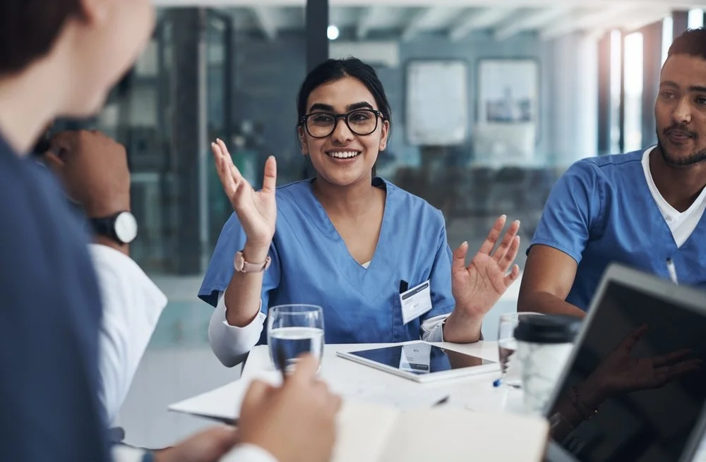 Medical team having a discussion in a conference room with digital devices on the table.