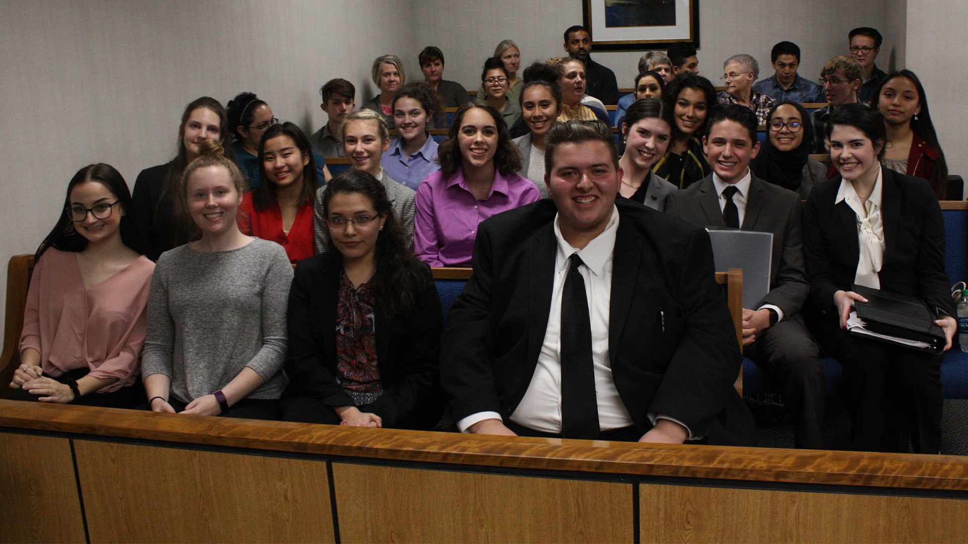Group of students sitting in a lecture hall, smiling for a group photo.