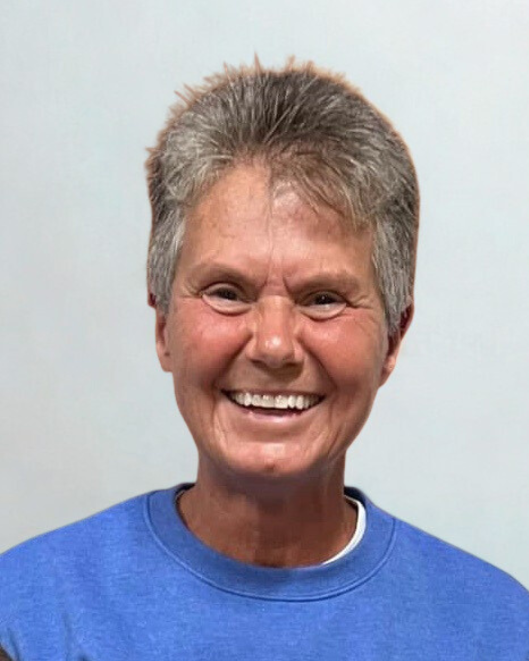 Smiling woman with short gray hair wearing a blue shirt.