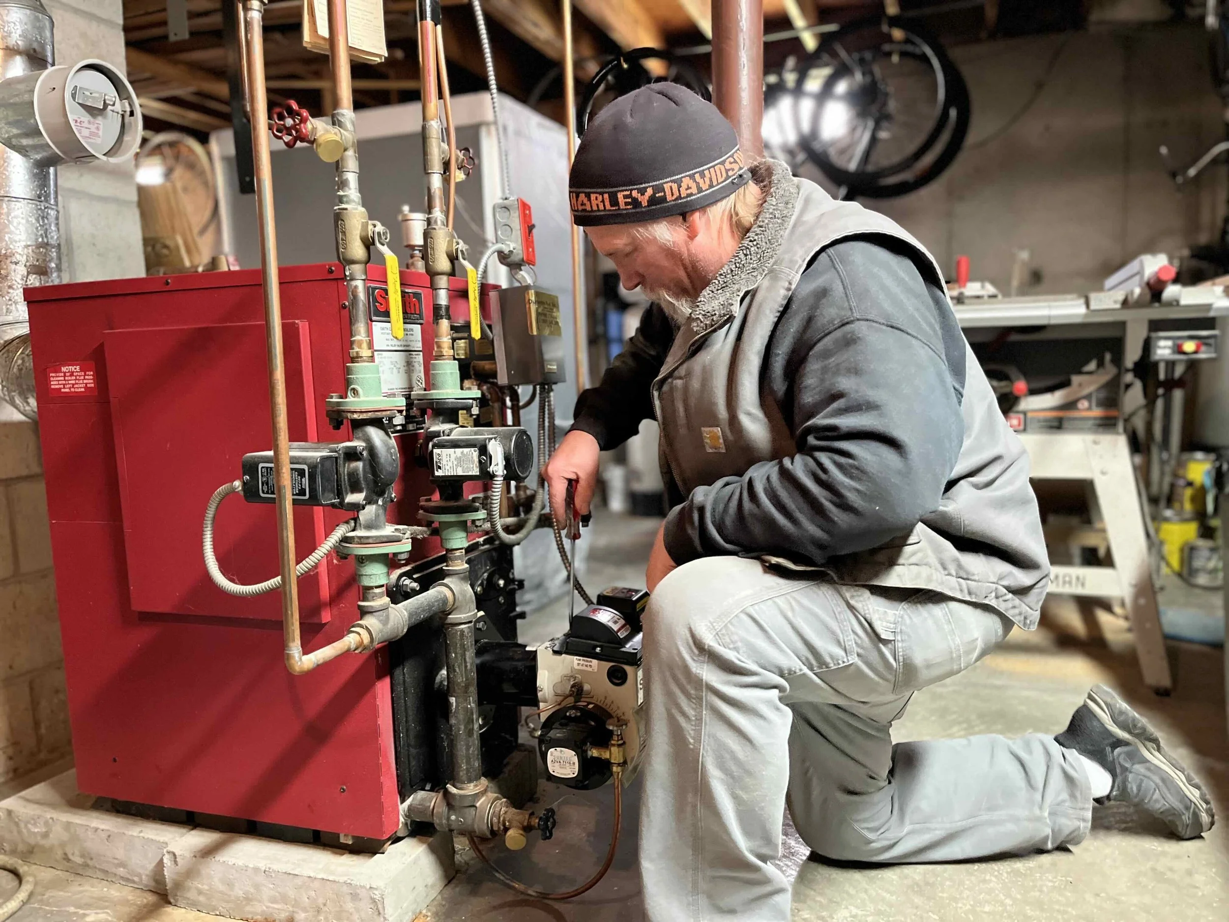 Dunbarton Fuel's JR Swindlehurst working on a boiler or furnace in a customer's basement.