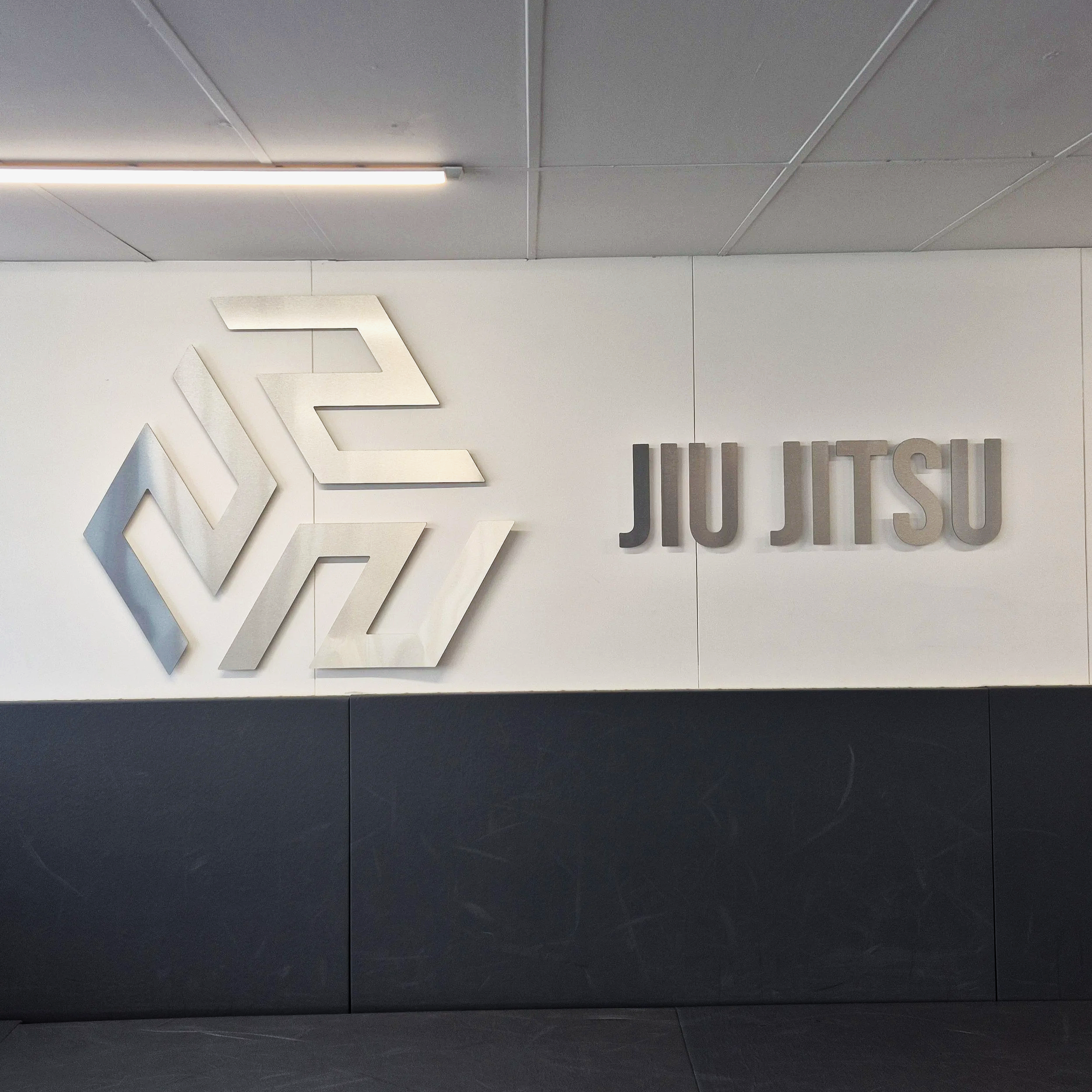 Modern office wall with illuminated logo and text in the background, gray and white color scheme, professional setting.