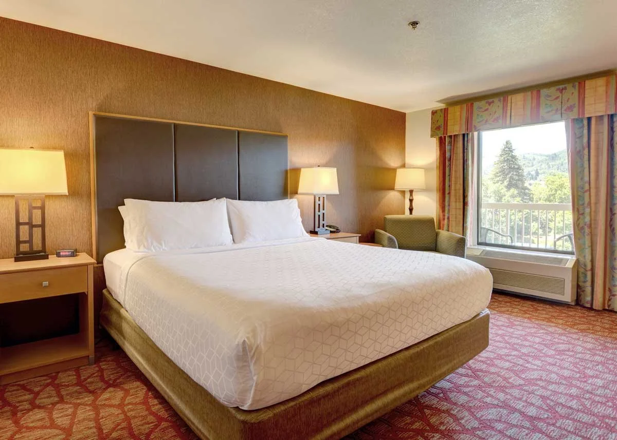 Hotel room with king sized bed, two nightstands and sitting area overlooking a private balcony