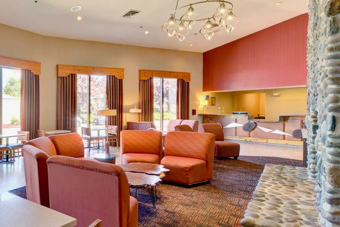 Hotel lobby sitting area with grand river rock fireplace and reception area for guest check-in