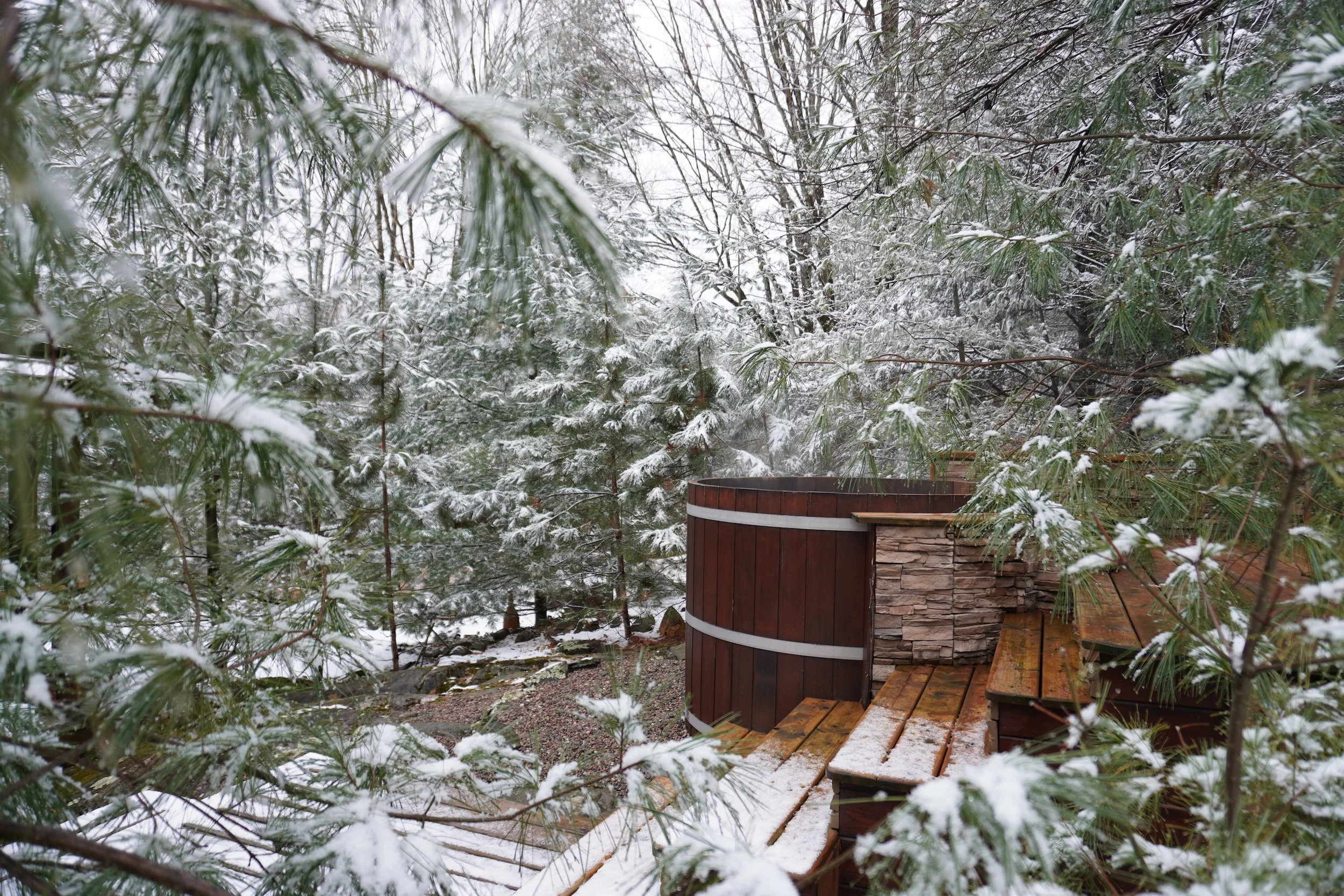 Snow covered trees surrounding your cedar hot tub at the luxurious and private Black River Retreat couples resort