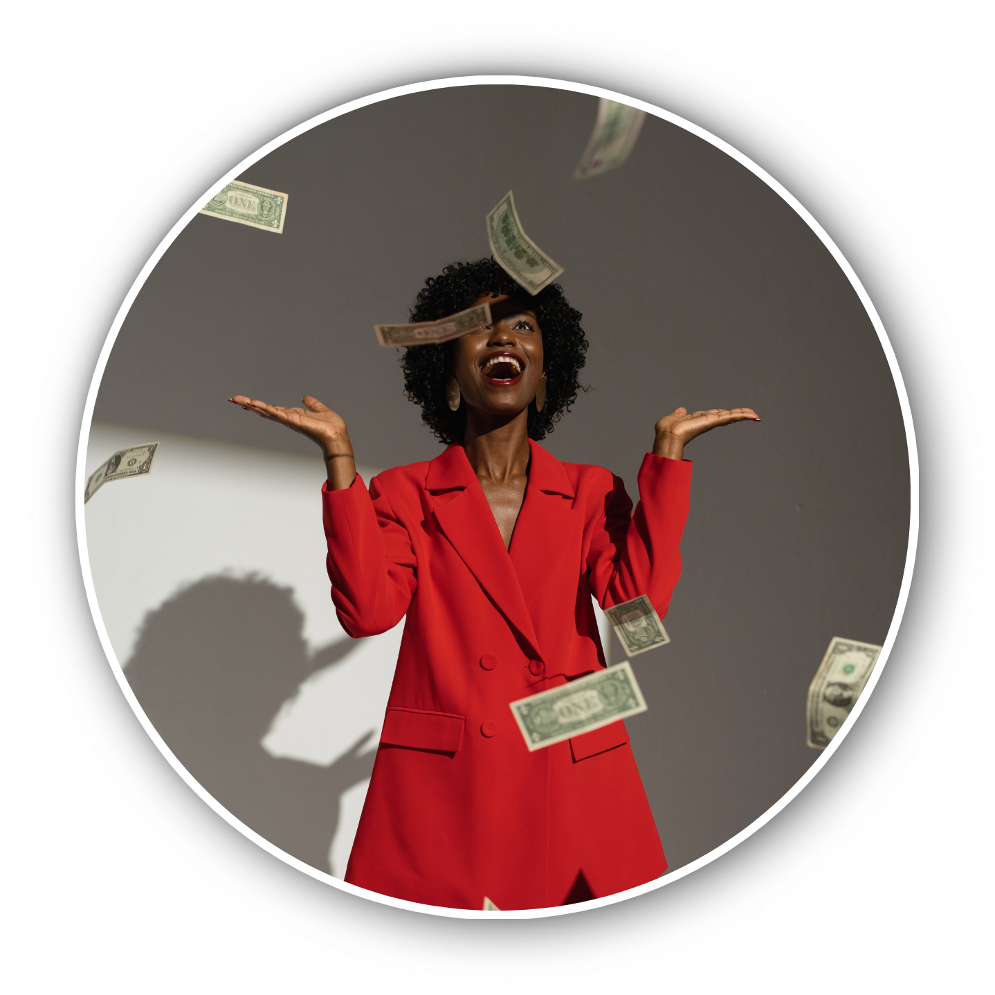 Happy woman wearing red blazer with dollar bills falling around her.