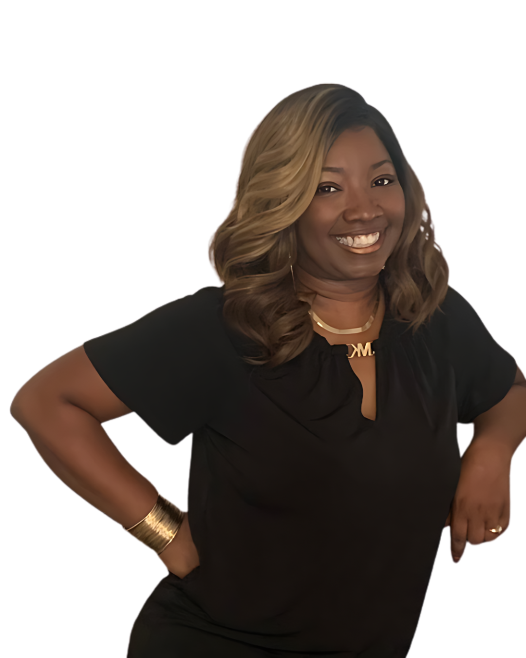 A woman with long, wavy, blonde and black hair, wearing a black top with short sleeves, a gold necklace, and a gold bracelet, smiling with her hands on her hips.