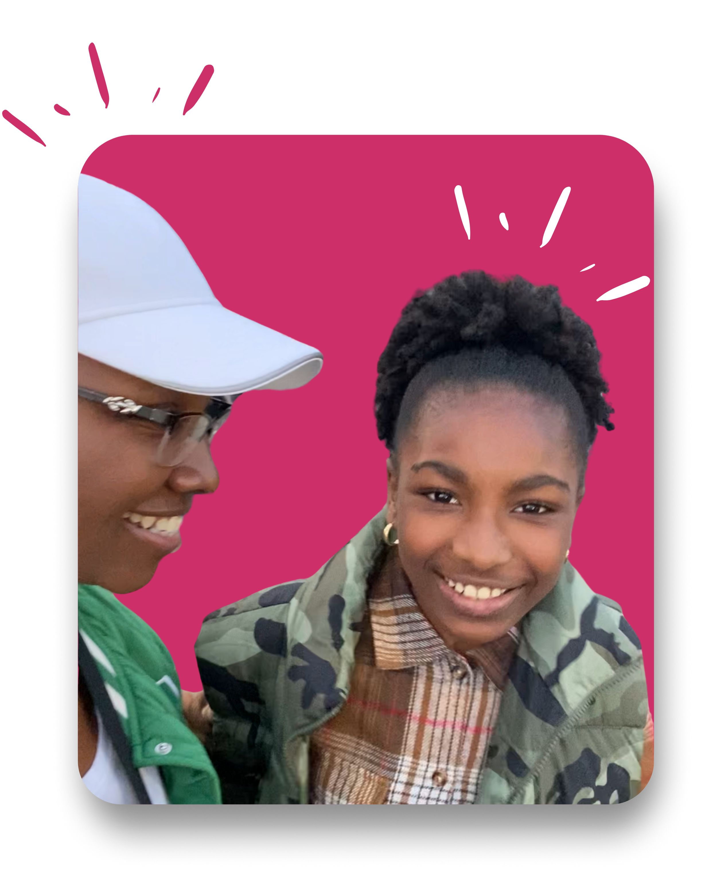 Two women smiling, one on the left wearing a white cap, glasses, and a green jacket, the other on the right with a short natural hairstyle, a camouflage jacket, and a plaid shirt, against a pink background.