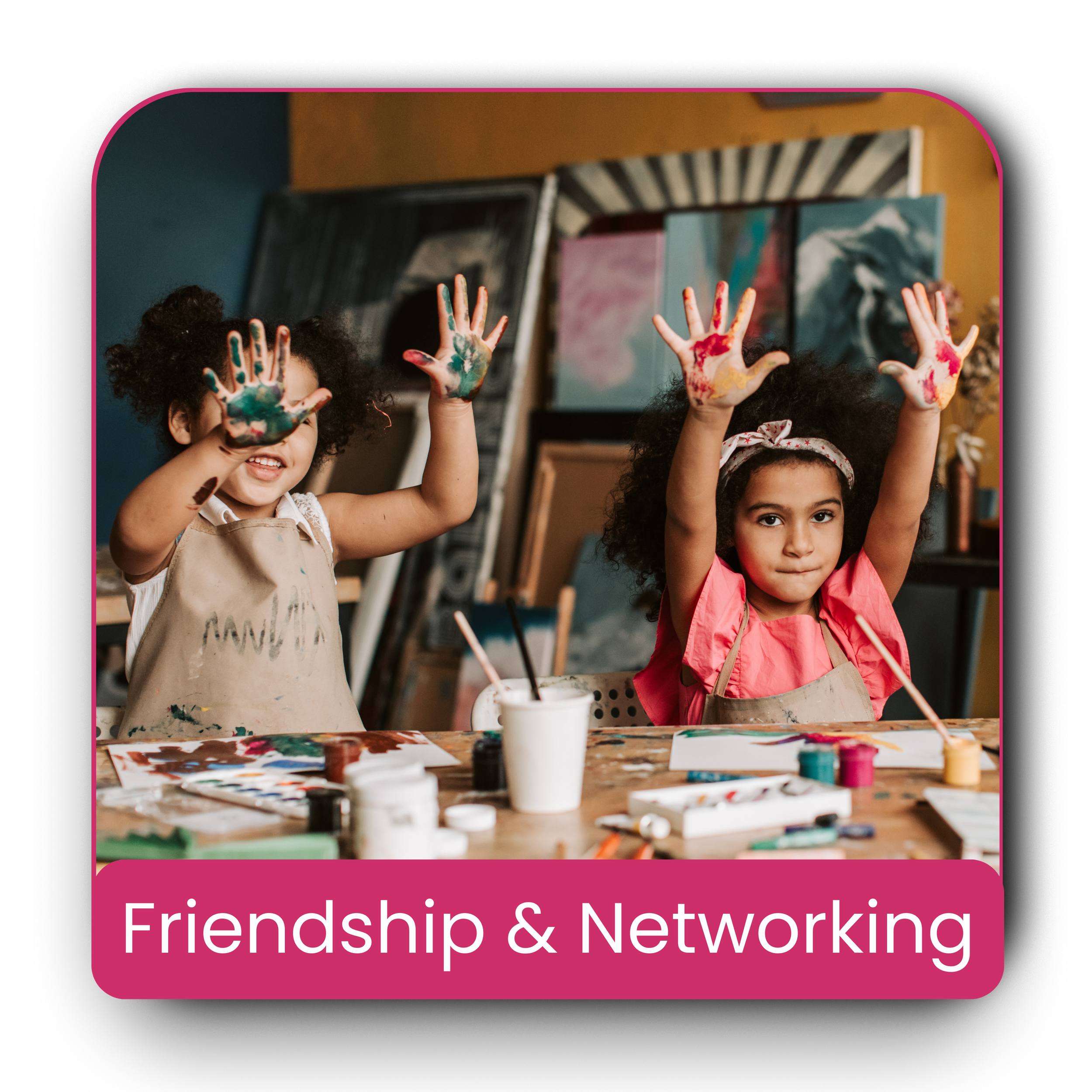 Two young girls smiling and raising their hands covered in paint, sitting at a table with art supplies in an art studio. Background features artwork and supplies. Caption reads 'Friendship & Networking.'