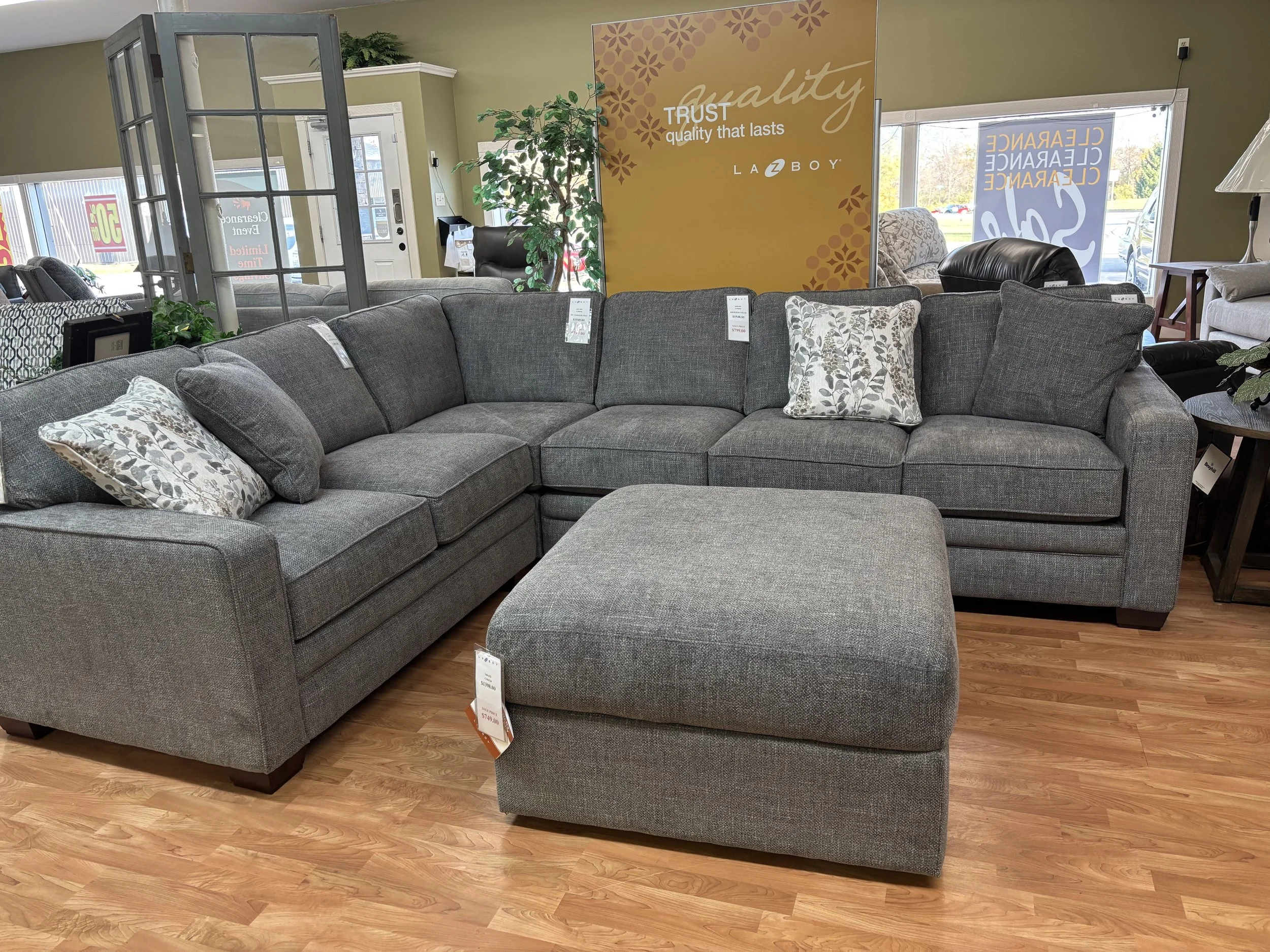 Gray sectional sofa with patterned pillows in a furniture store display area.