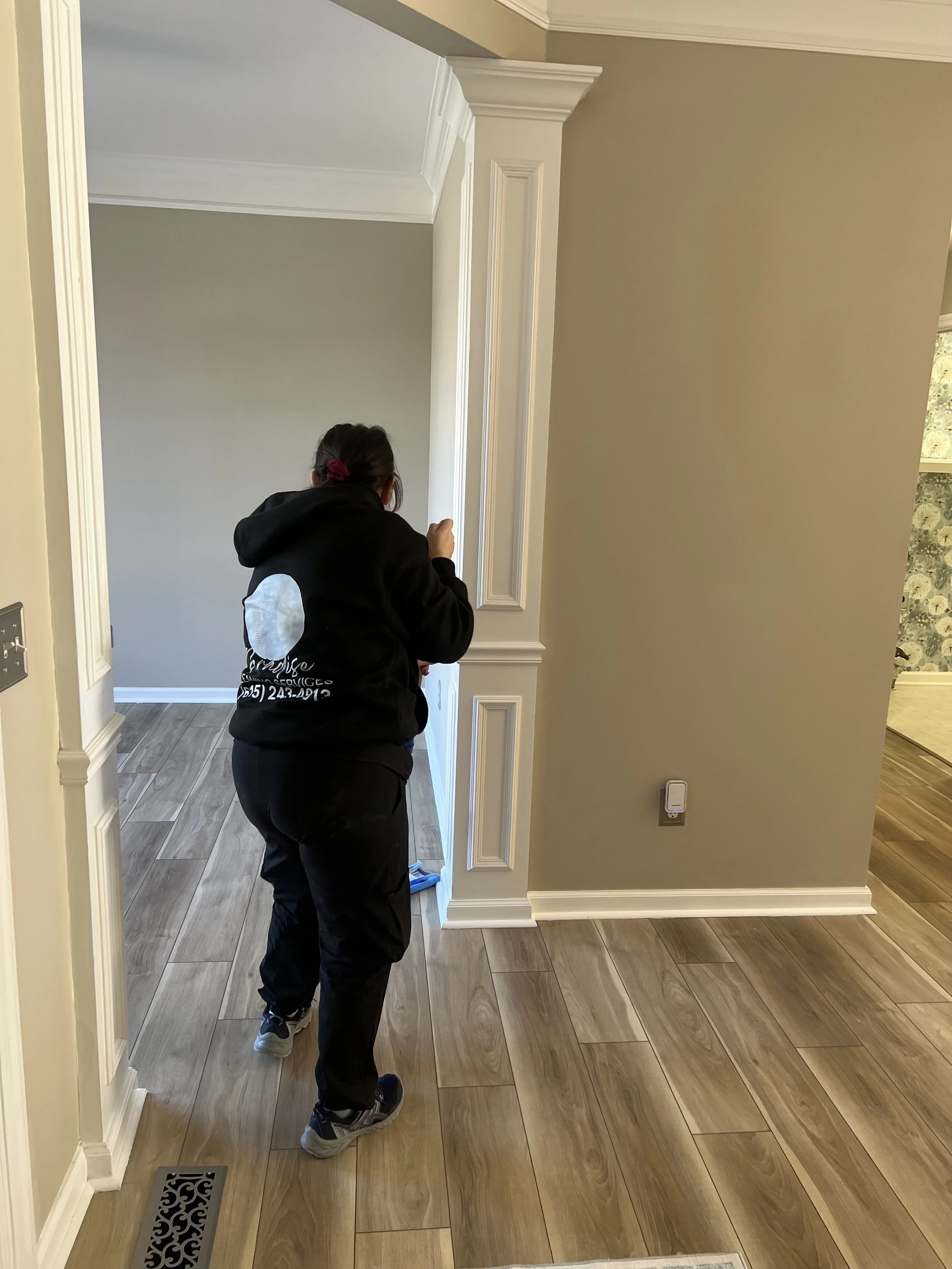 Cleaning professional walking across freshly cleaned hardwood floor in home interior.