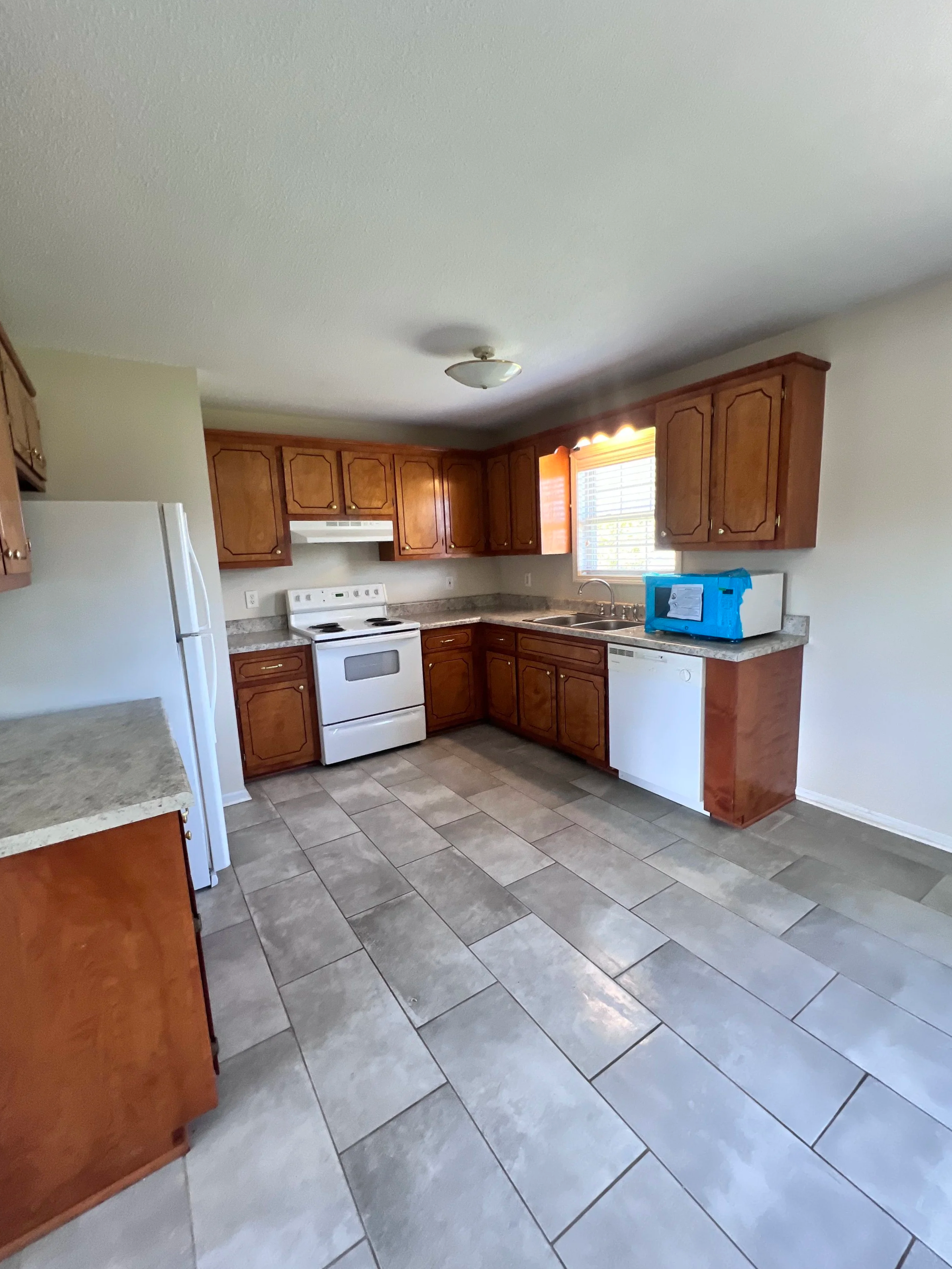 Vacant kitchen with wood cabinets sanitized during move-out cleaning service.