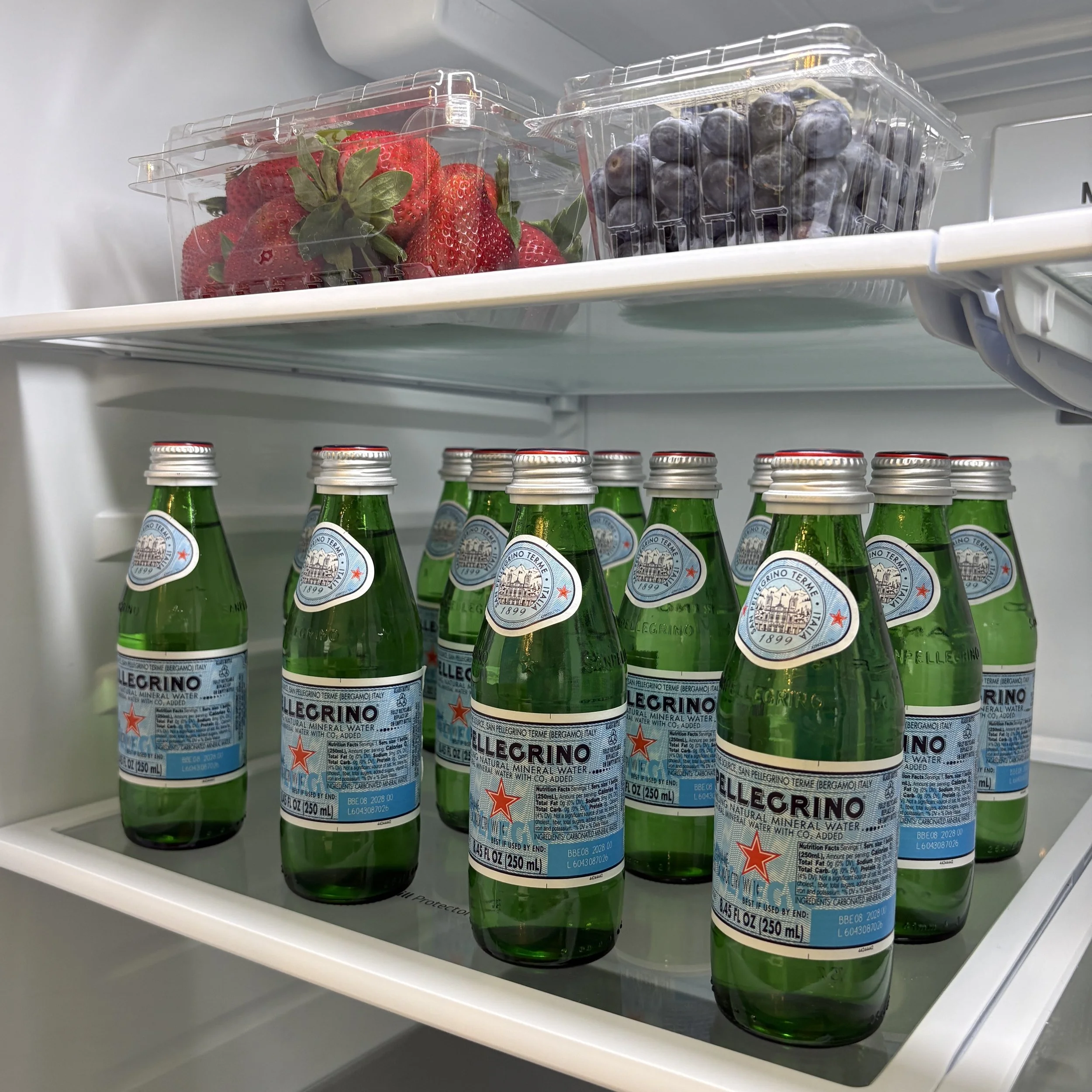 Hotel mini fridge stocked with sparkling water, fresh strawberries, and blueberries from a Nashville grocery delivery service