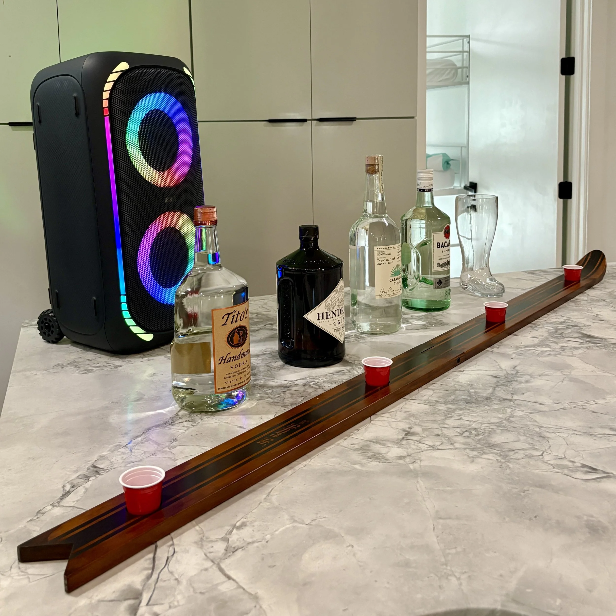 Nashville Airbnb bar setup with a Bluetooth speaker, liquor bottles, and a shot ski for a party drinking accessories rental