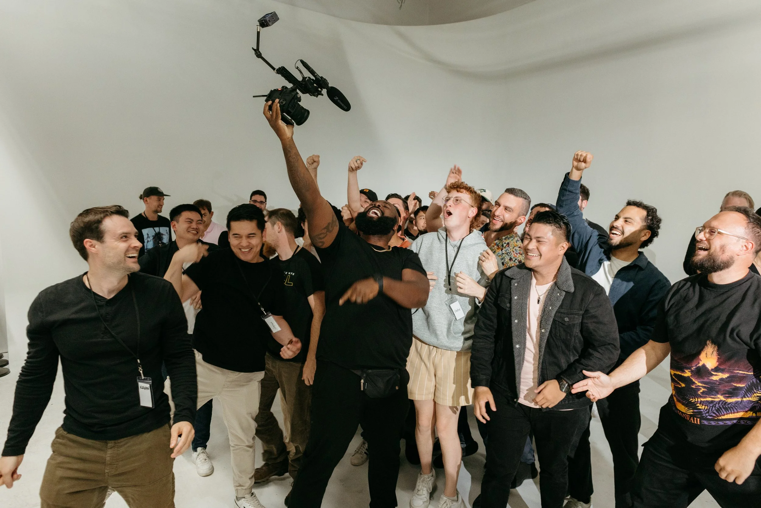Group of people cheering and celebrating with joy, some raising fists, in a bright indoor setting.