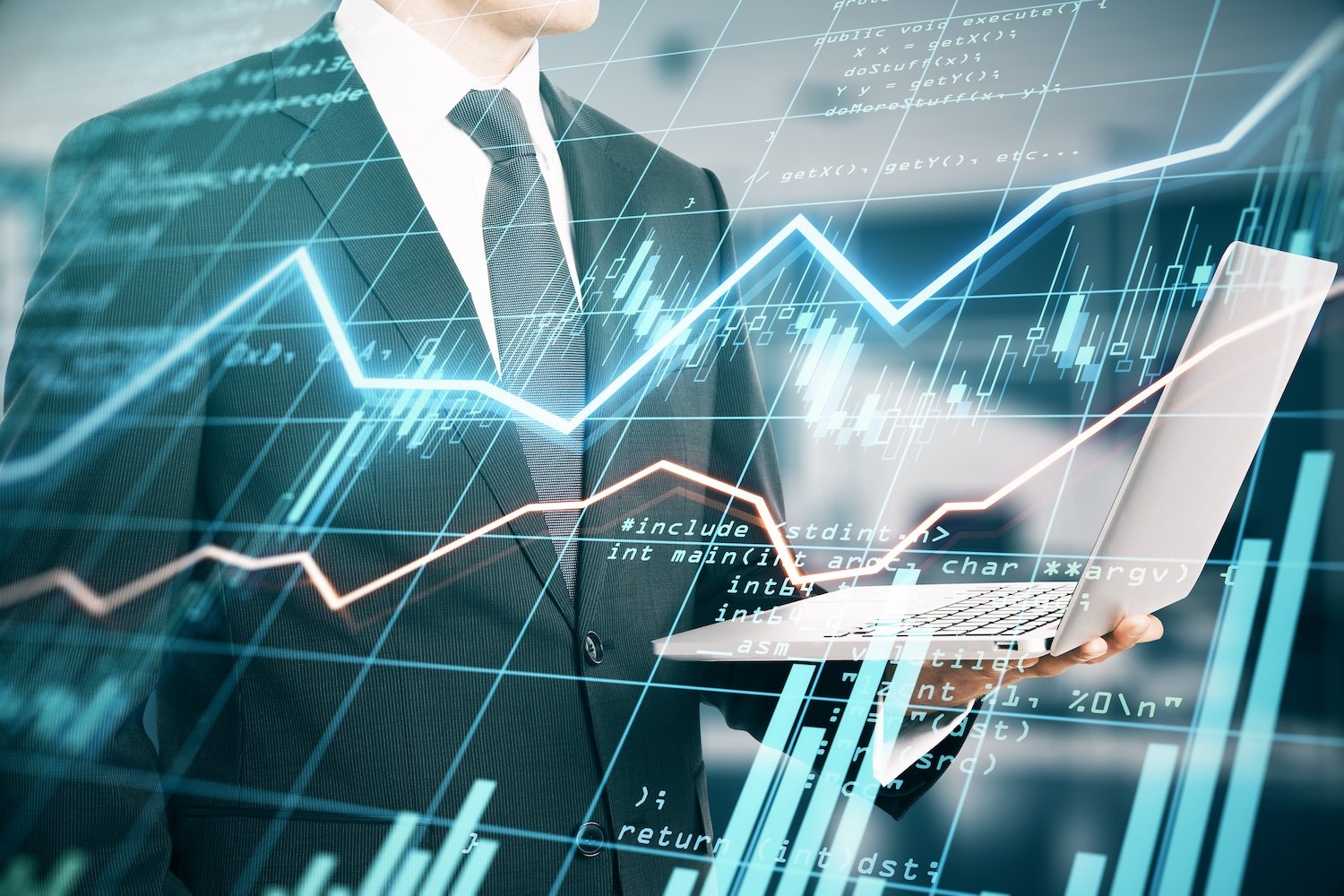 Businessman in a suit holding a laptop with overlaid financial graphs, charts, and computer code indicating data analysis or stock market trends.